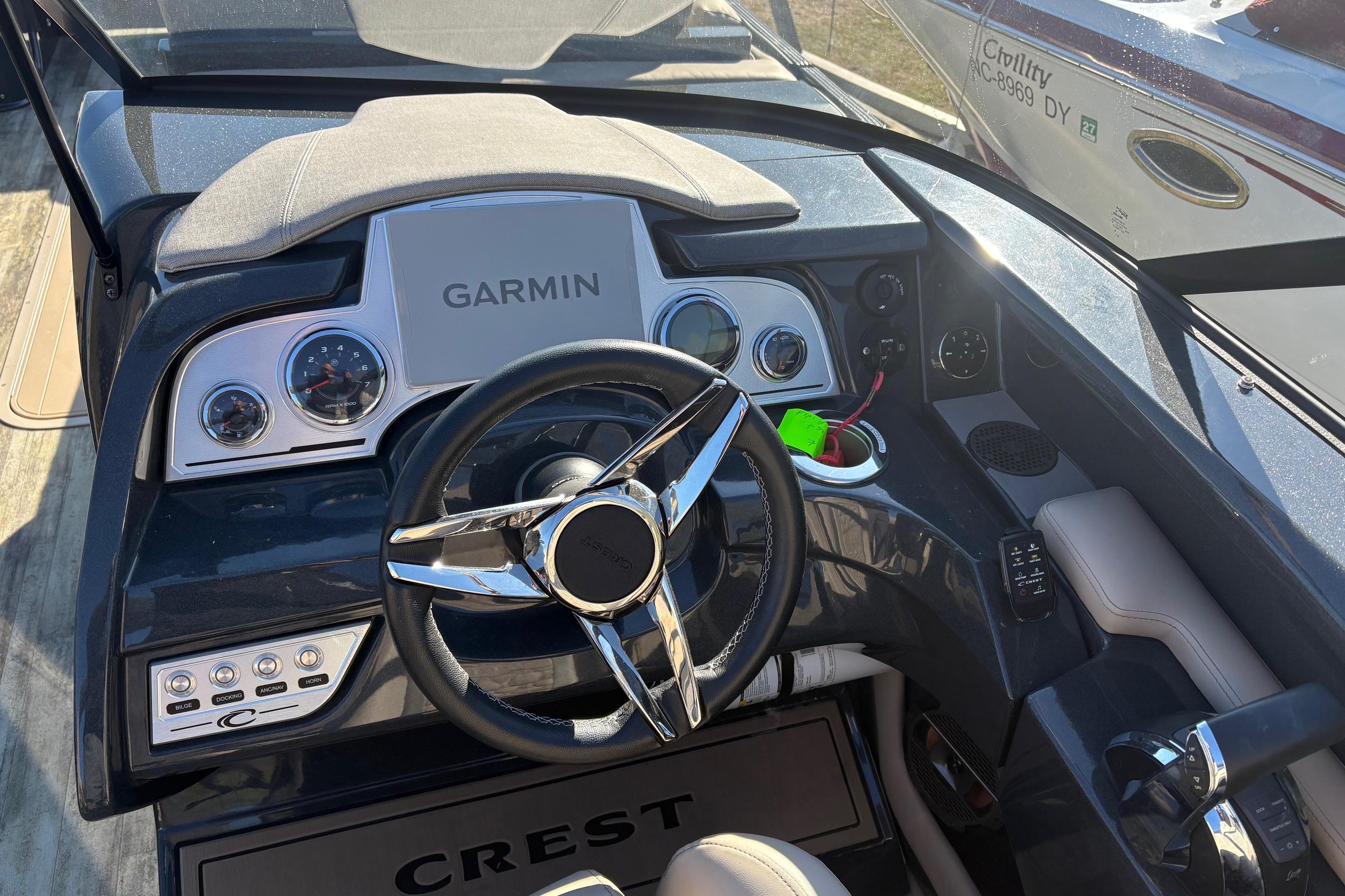 Cockpit of 2022 Crest Continental 250 boat with Garmin navigation system and sleek steering wheel.