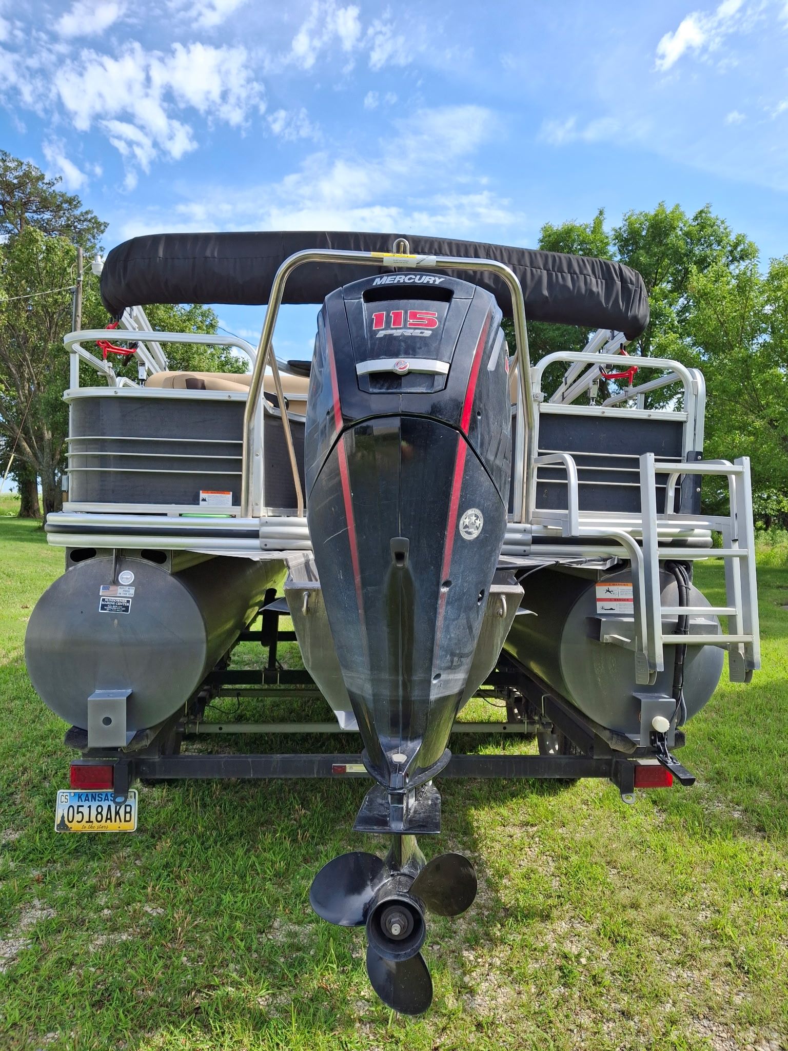 A Lowe SF 214 Sport Fish pontoon boat on a trailer in a grassy area.