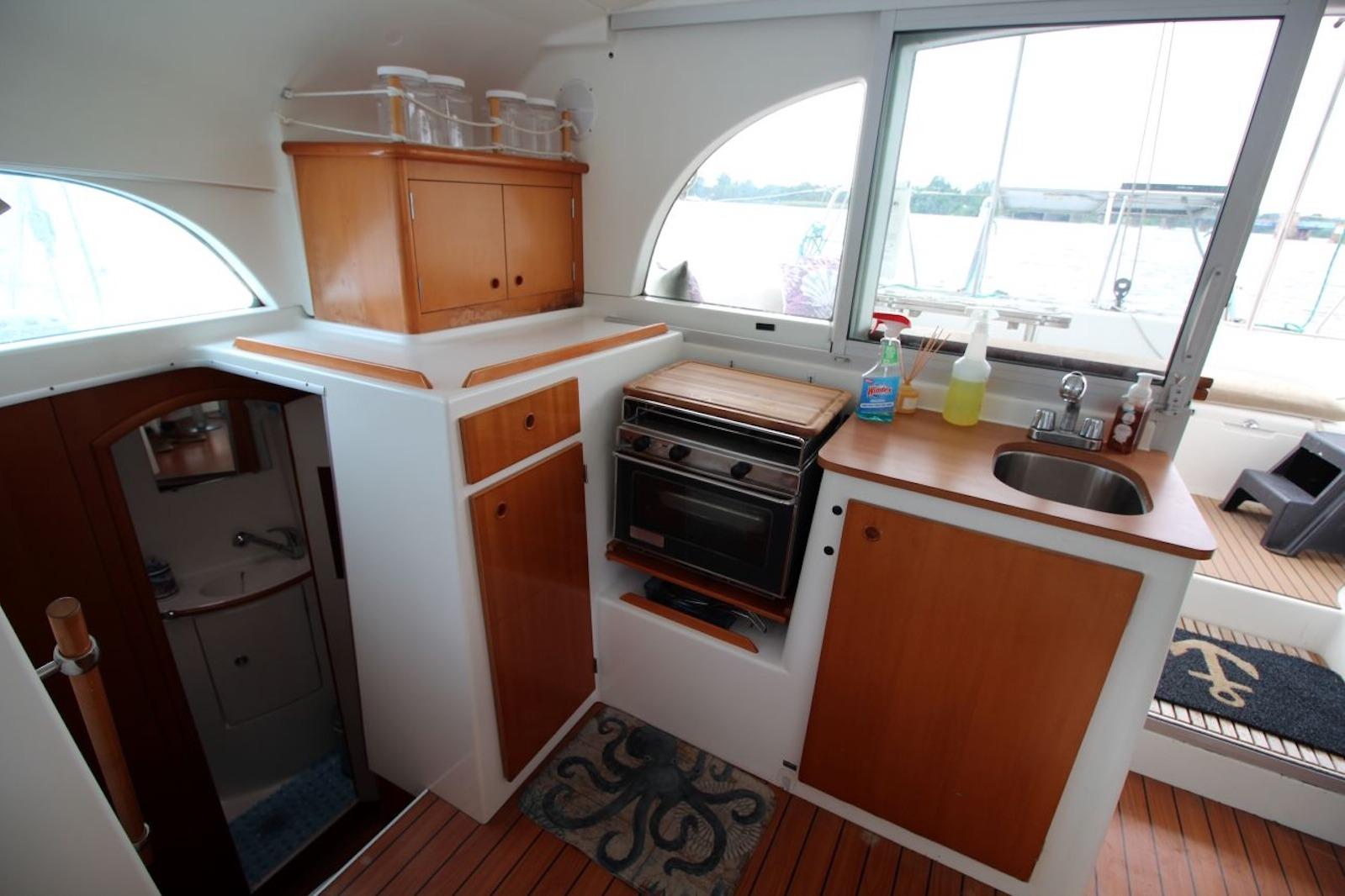 Interior of 2004 Lagoon 380 catamaran kitchen with wooden cabinets and appliances.