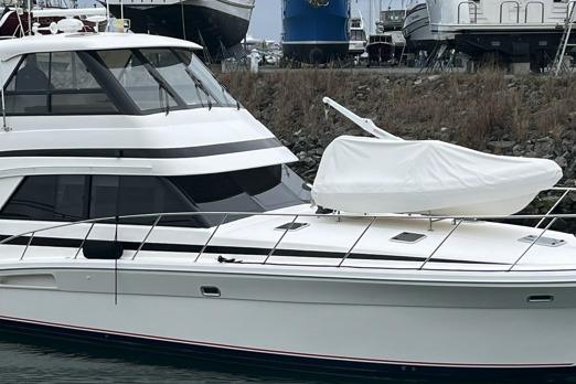2000 Riviera Enclosed Flybridge yacht docked, featuring sleek design and covered equipment on deck.