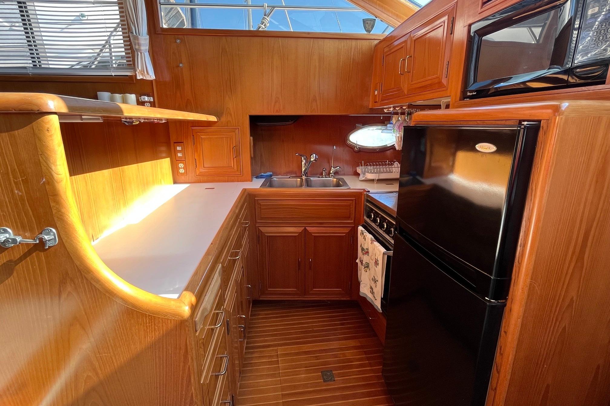1989 Ocean Alexander 440 Sundeck CPMY kitchen with wood cabinetry, black appliances, and ample counter space.