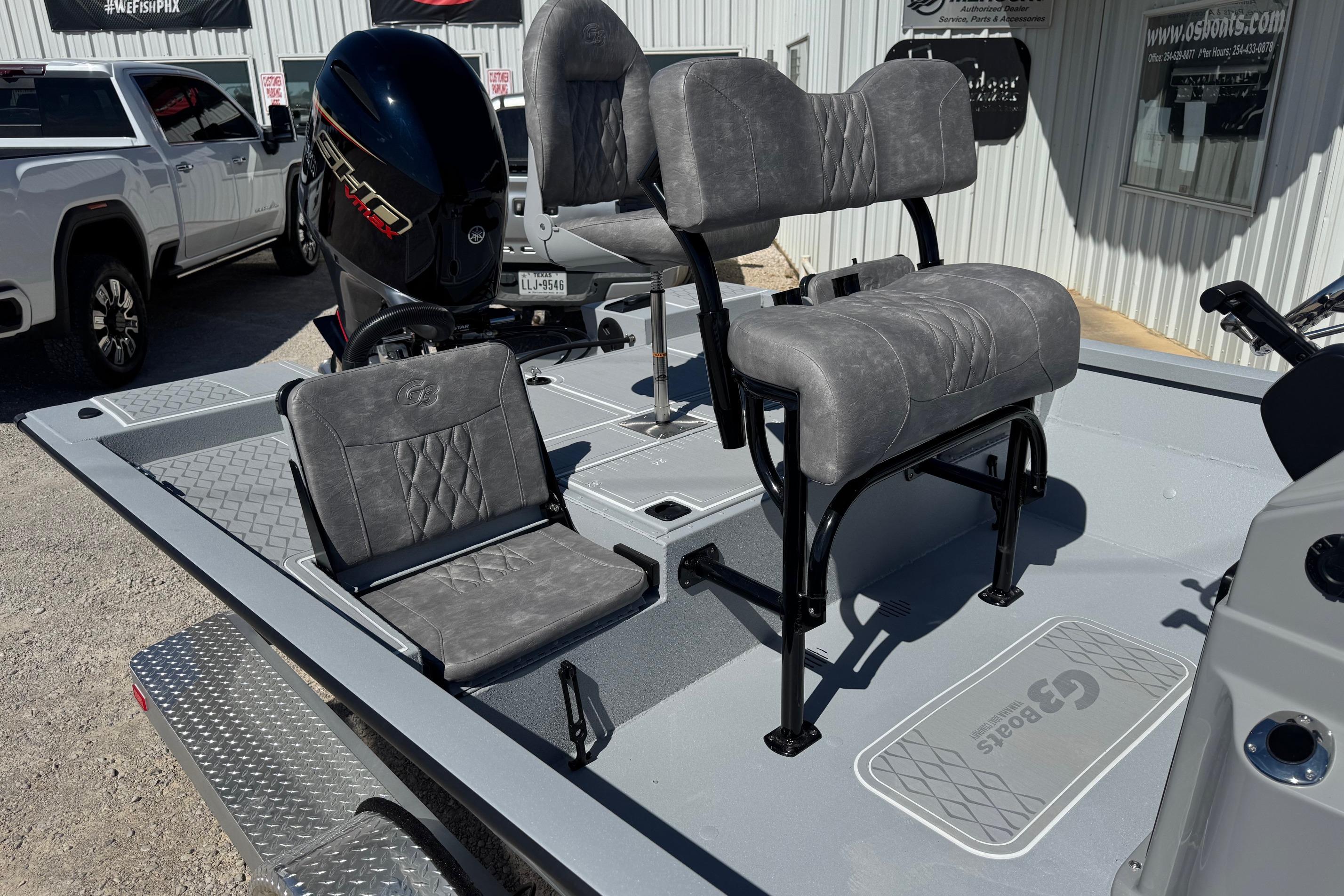 2026 G3 21GX boat interior with gray seating and motor, parked near a building.