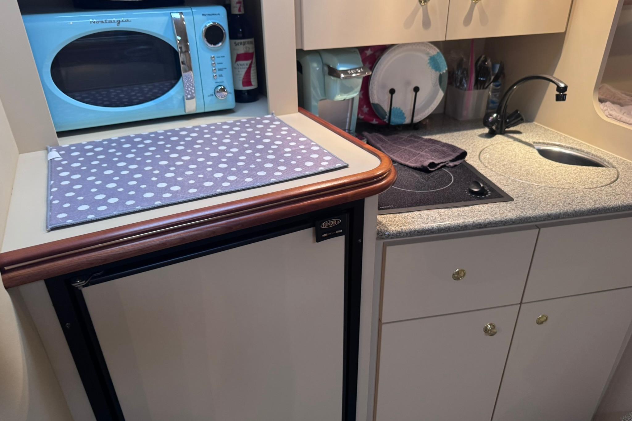 Compact yacht kitchen with microwave, sink, and stove in 2002 Cruisers Yachts 3275 Express.