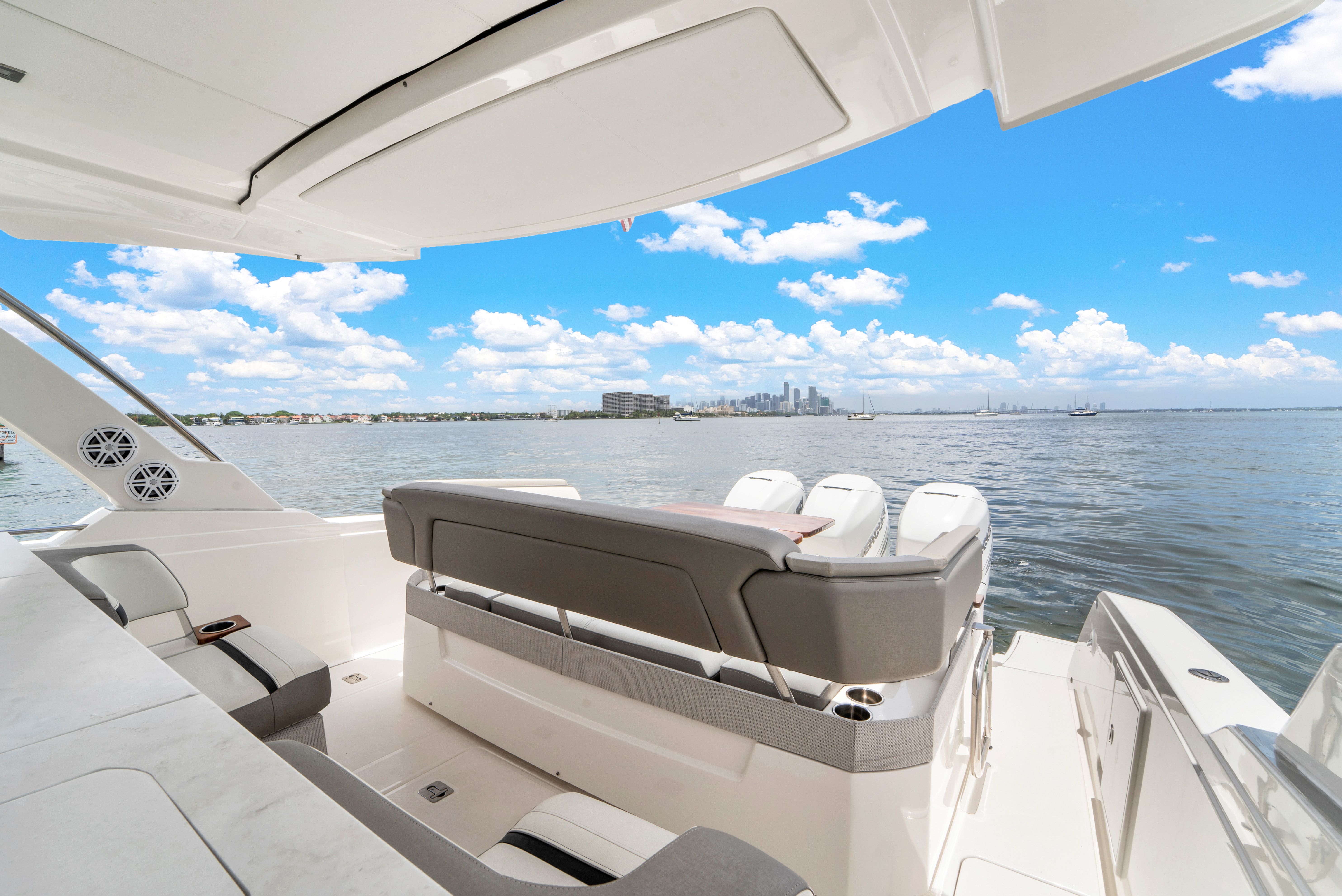 The image shows the stern of a Tiara Yachts 38 LS on the water with a city view.