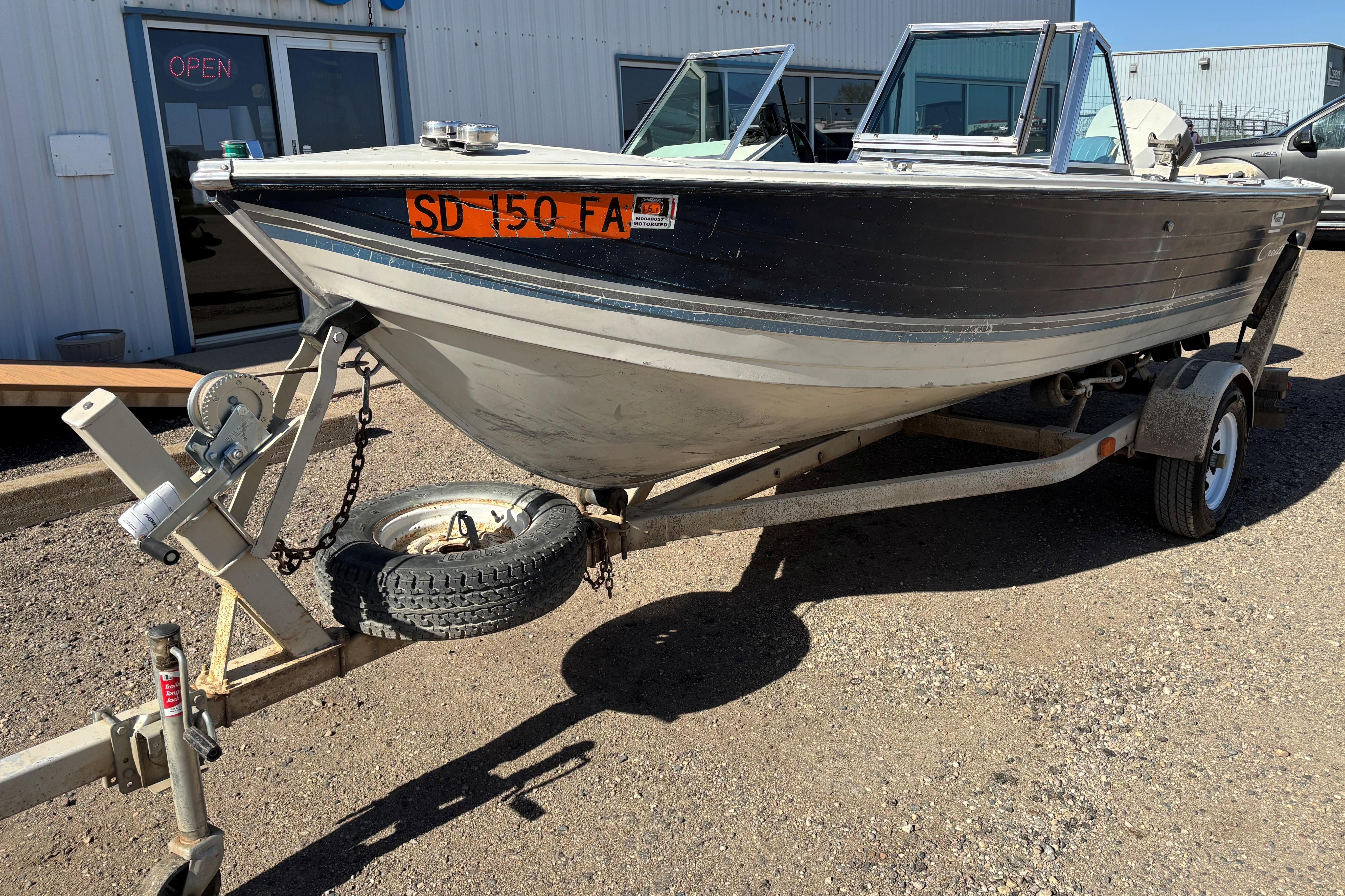 1983 Crestliner 16 boat on trailer, parked outside a building with an "Open" sign.