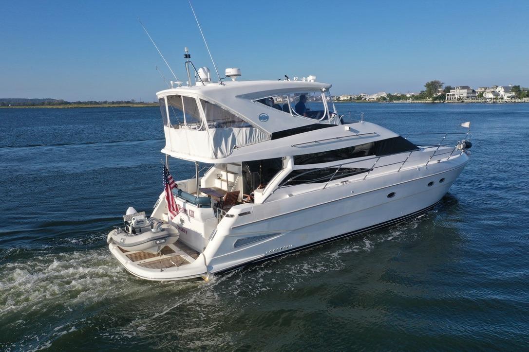 2005 Neptunus 56 Flybridge yacht cruising on a serene waterway.