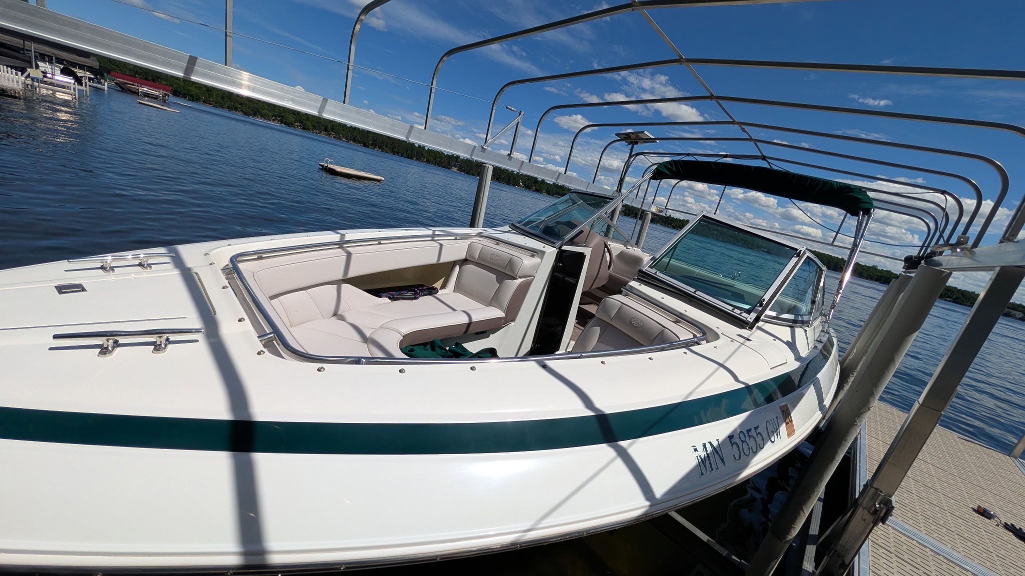 A 1995 Cobalt 222 boat docked. It features white upholstery and a green canopy.