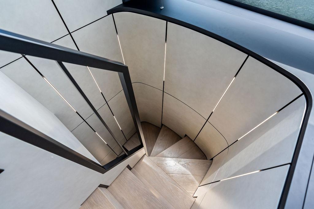 Modern spiral staircase inside 2025 Pershing GTX 80 yacht, featuring sleek design and ambient lighting.