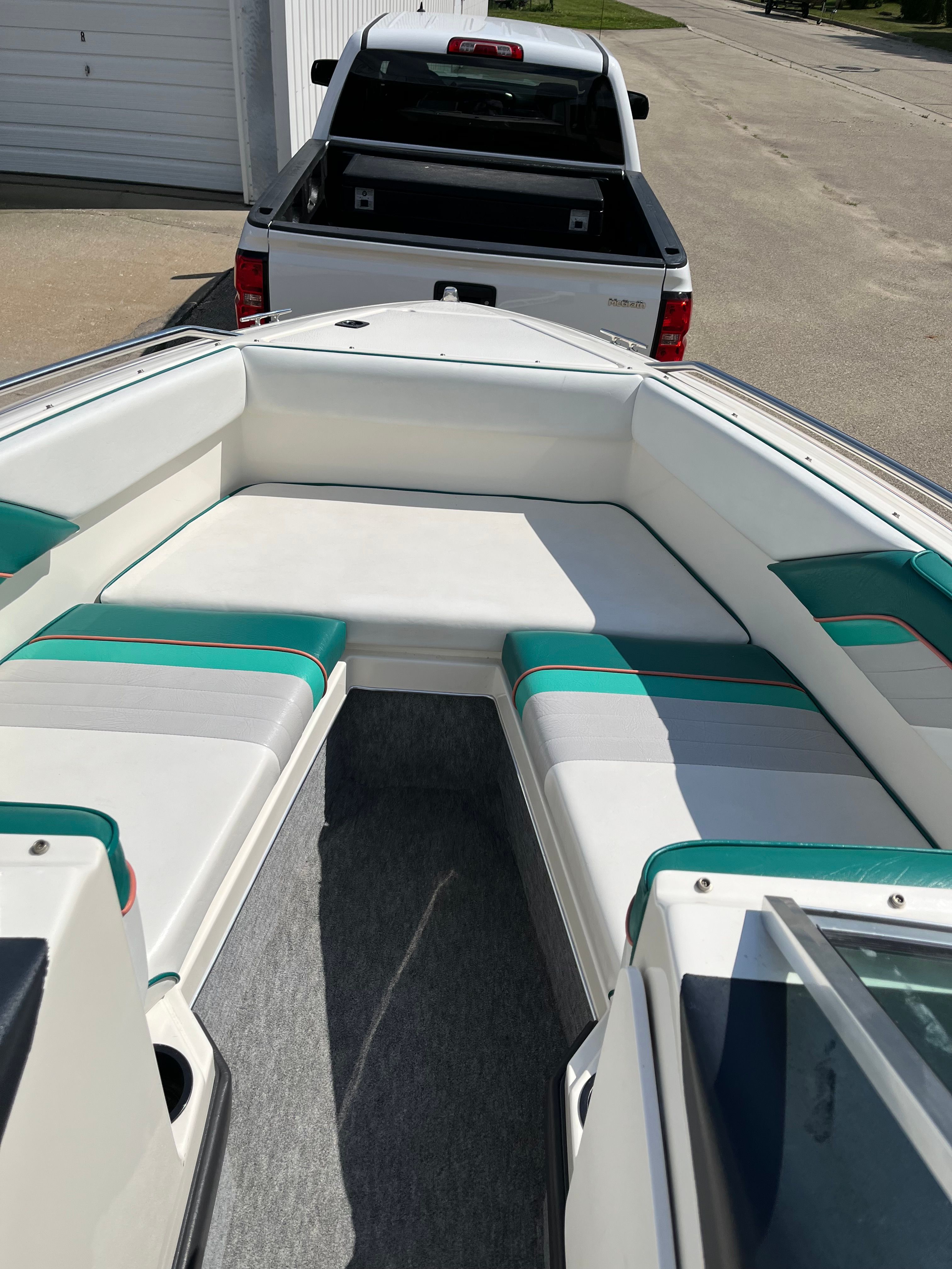A Sea Ray 220 Bow Rider boat with white and green seats, parked on a trailer.