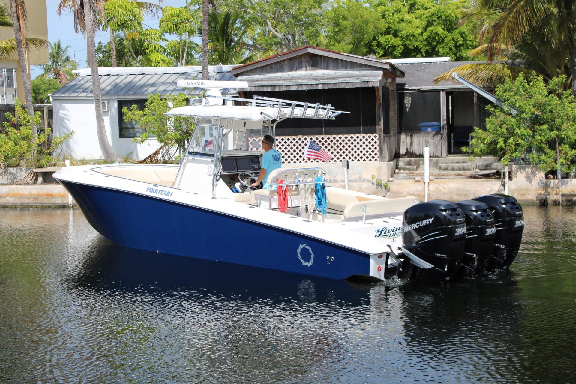 2007 Fountain 34 Center Console boat with triple Mercury engines on a calm waterway.