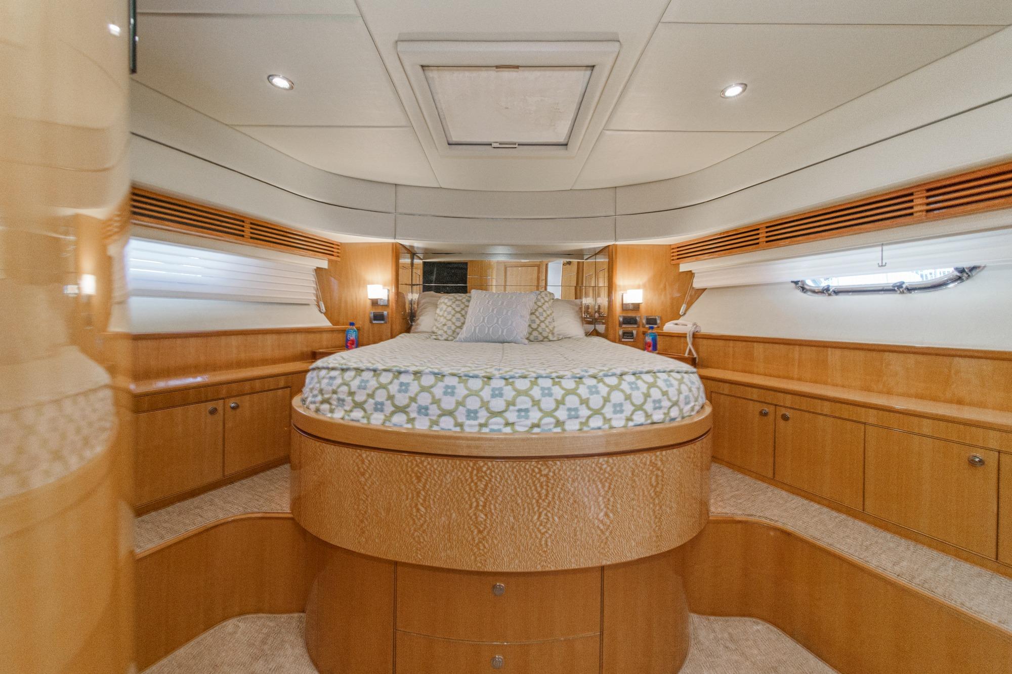 Luxurious Mystica 82 yacht bedroom interior, 2008 model, featuring elegant wood finishes and cozy bedding.