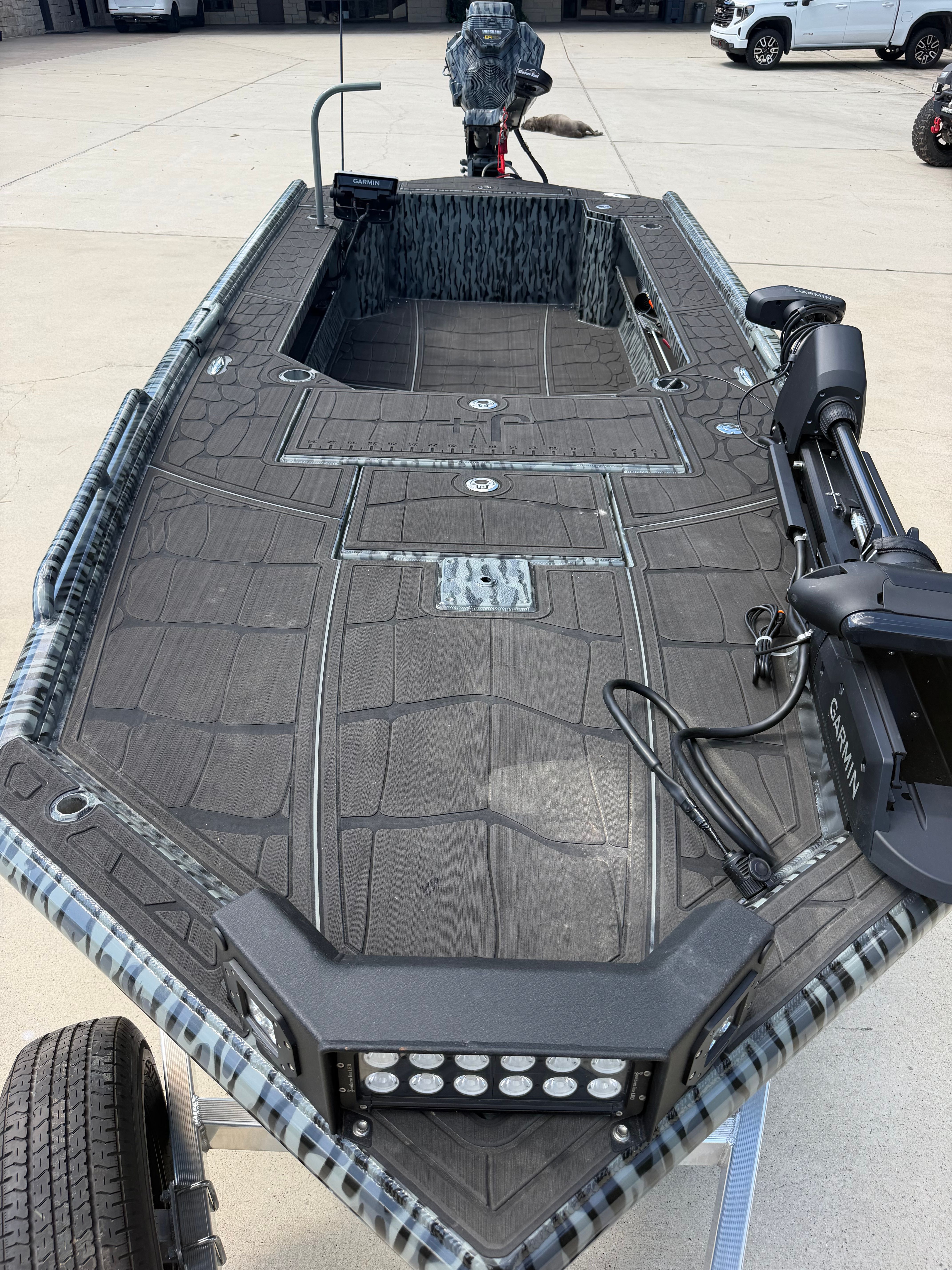 A modern boat with a gray deck and black motor on a trailer.