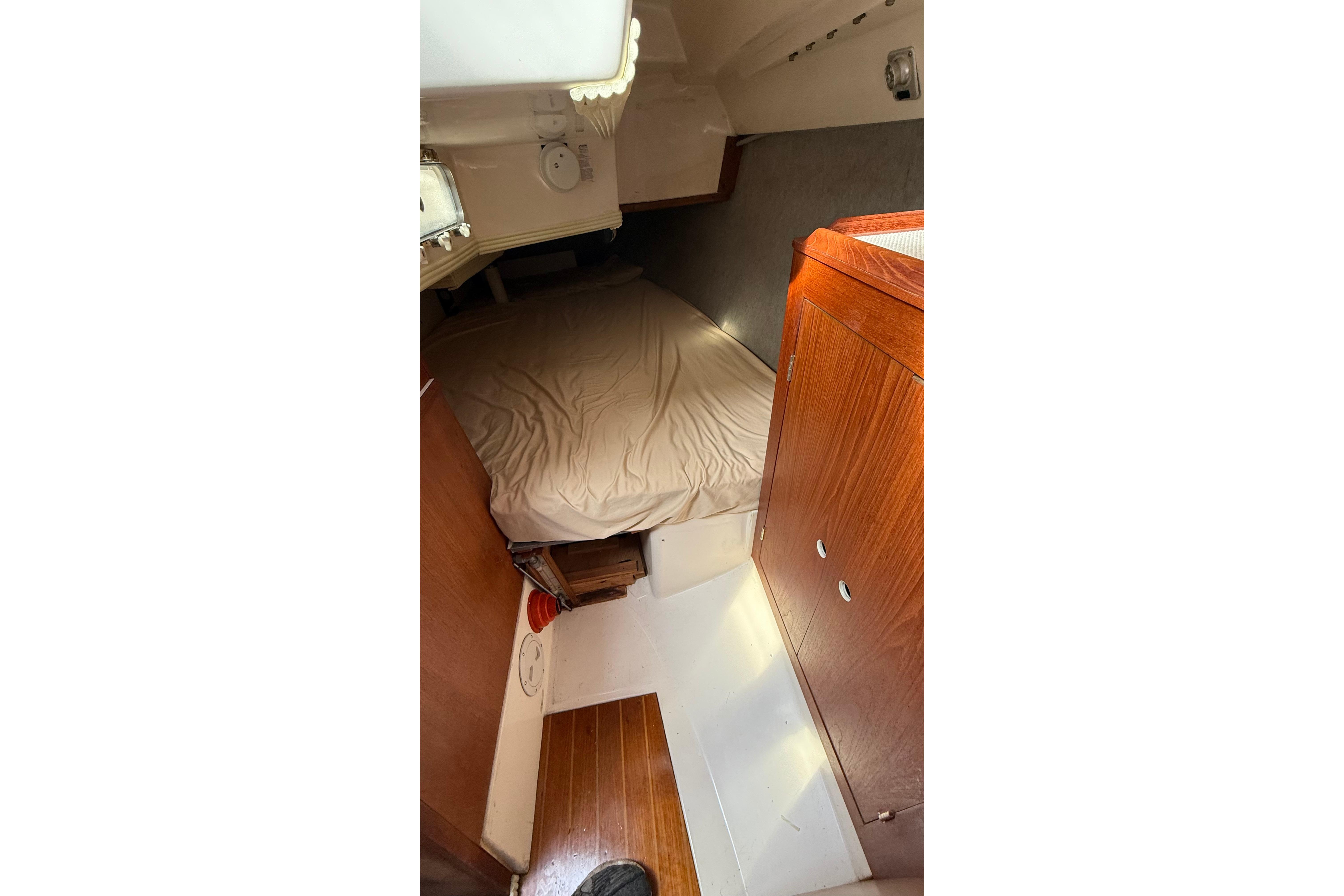 Interior cabin of 1984 Hunter 31 sailboat with wooden cabinetry and bed.