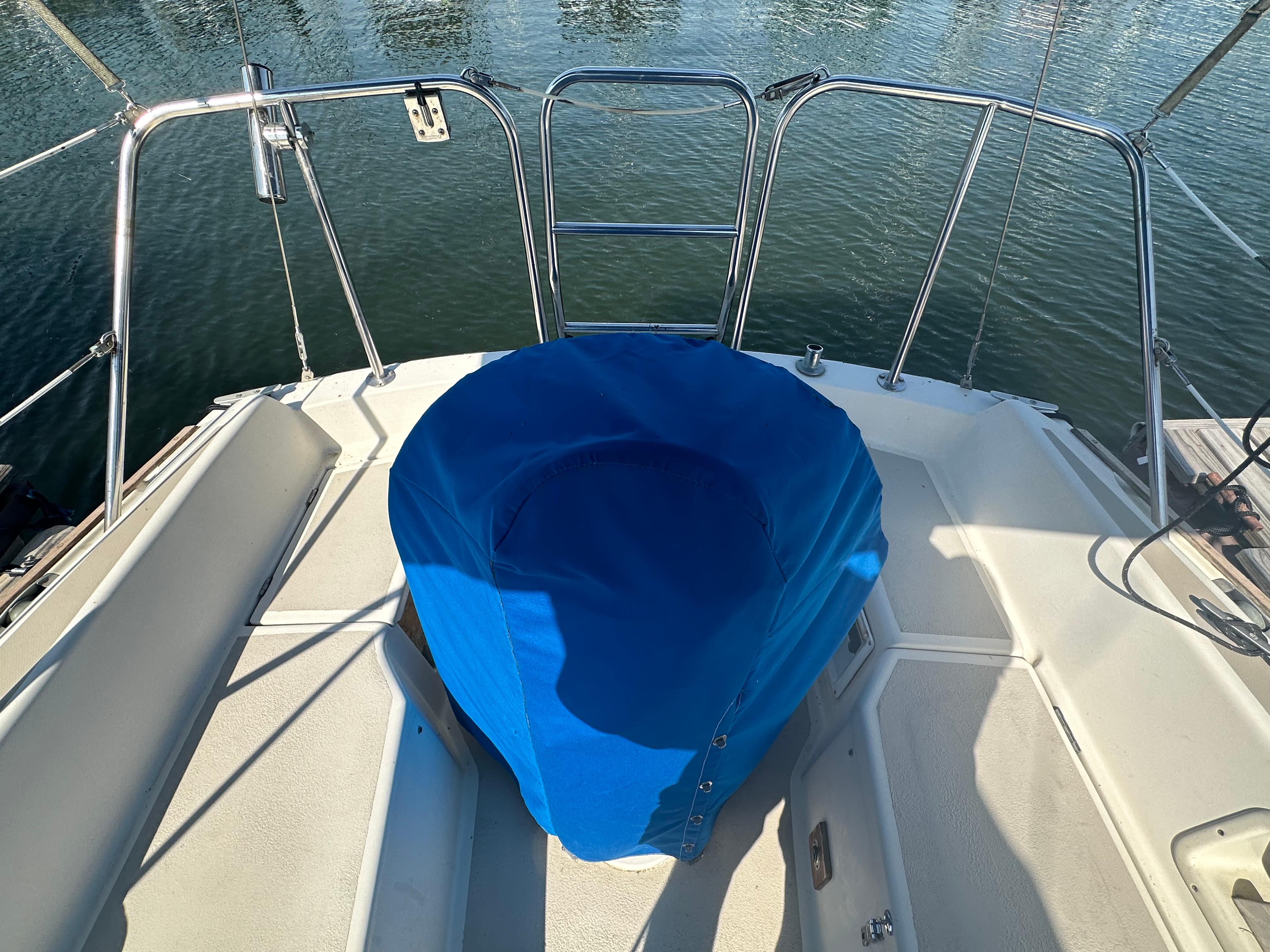 1983 O'Day 28 sailboat cockpit with blue cover, docked on calm water.