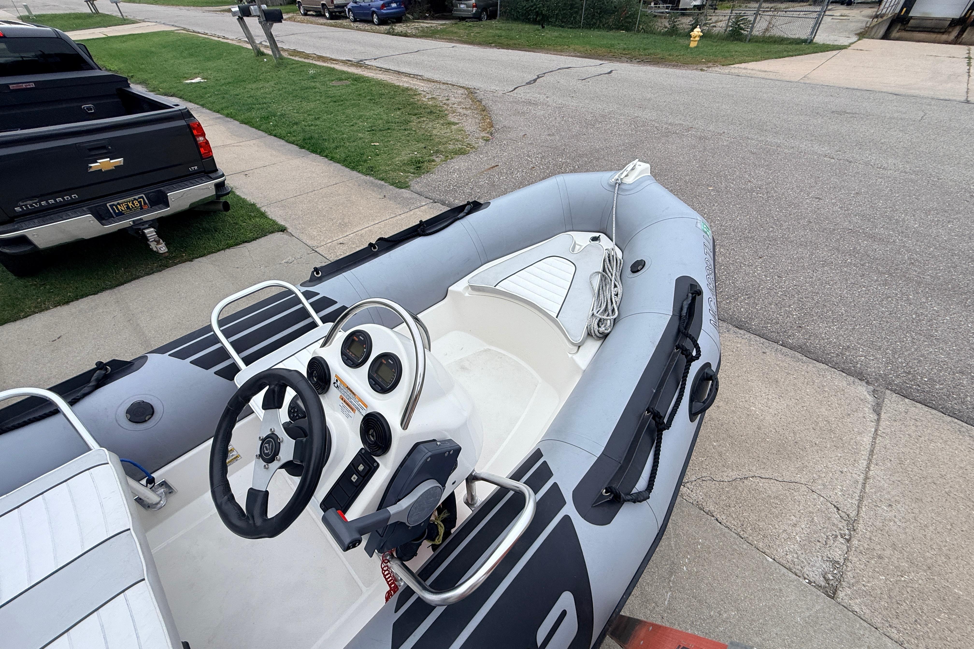 2014 Zodiac Pro Classic 420 inflatable boat parked on a street near a pickup truck.