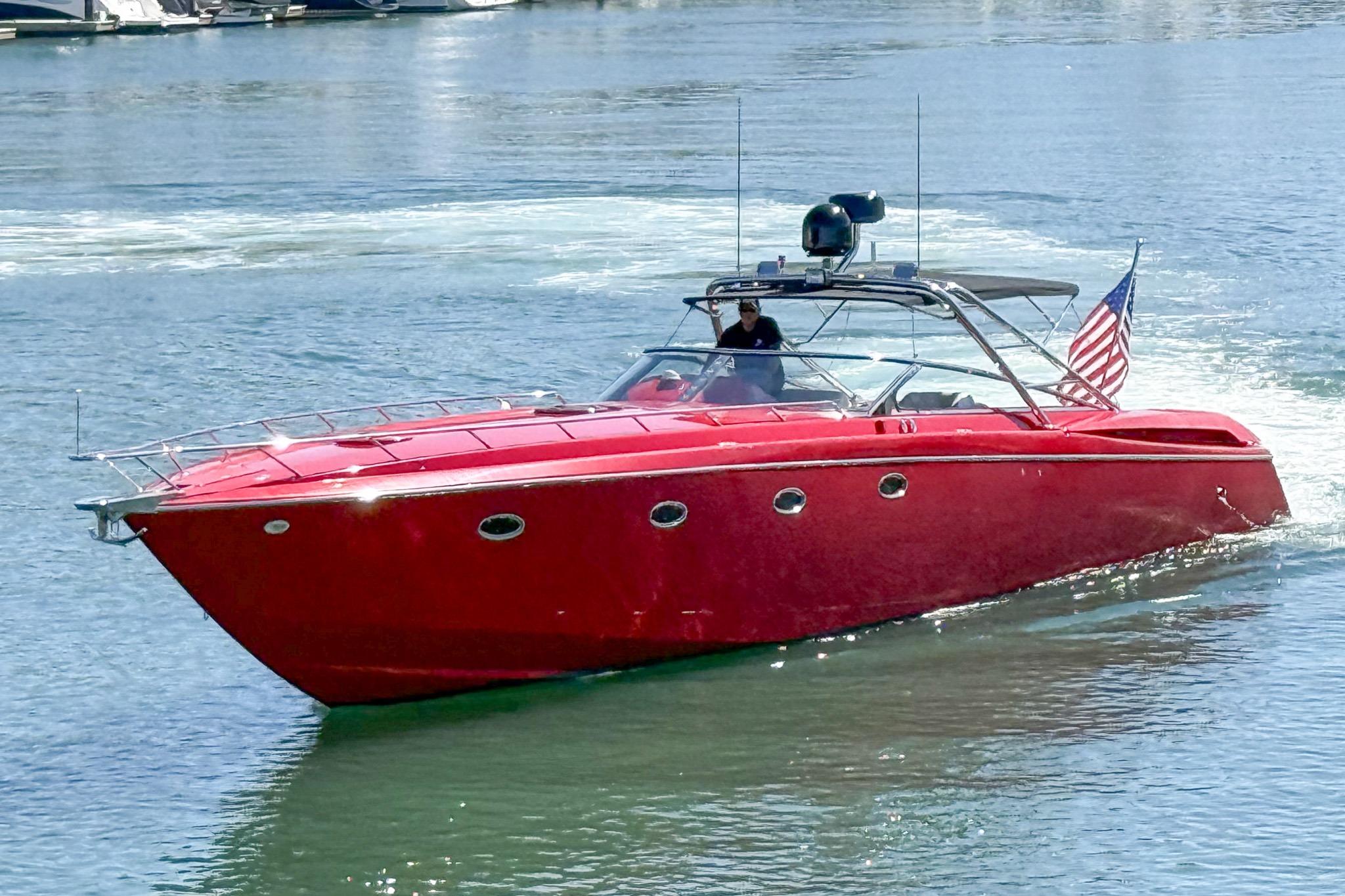 Red 2002 Hallett Custom High Performance Express Cruiser on water with American flag.