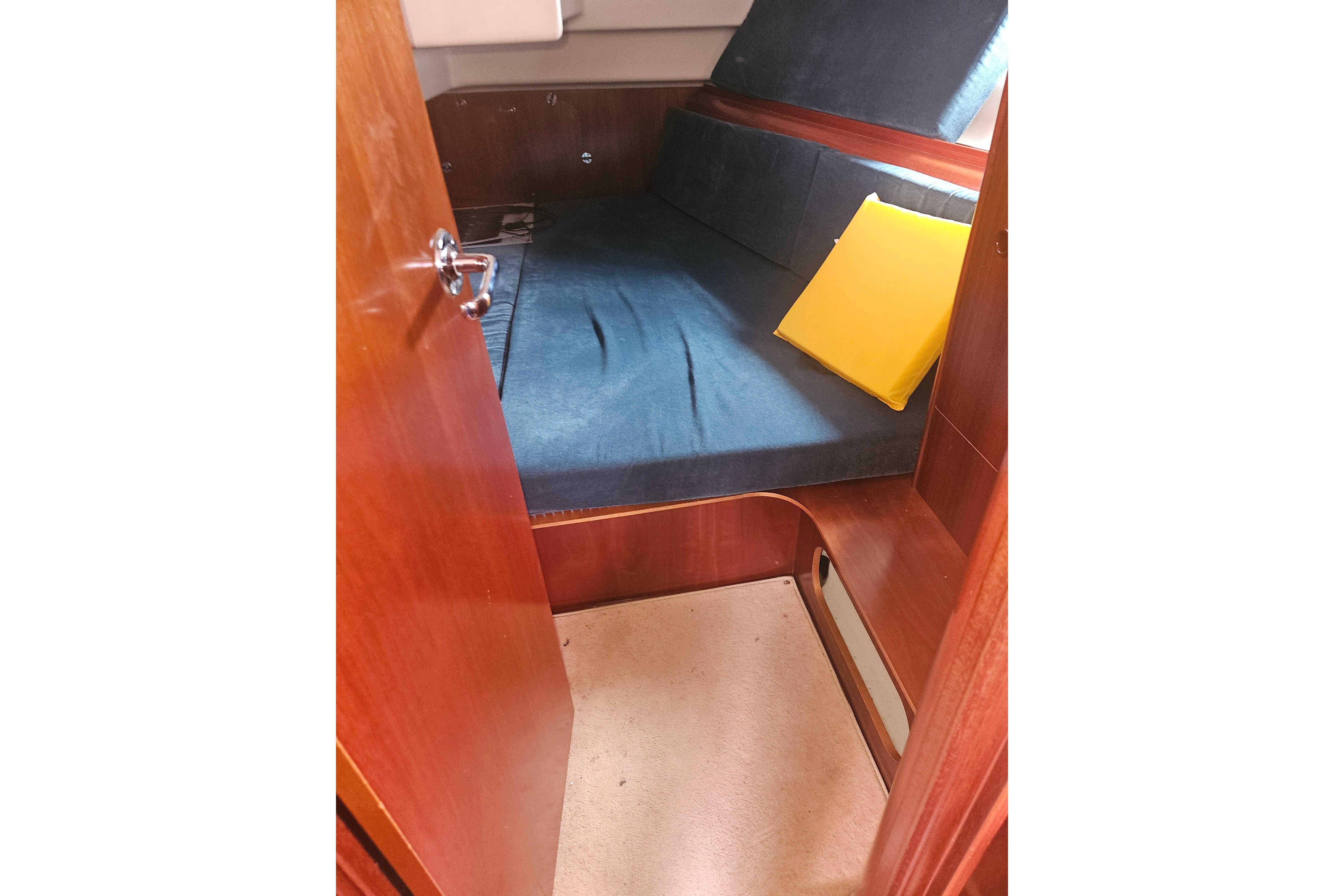 Cozy cabin interior of 1998 Beneteau Oceanis 381 sailboat with blue cushions and yellow pillow.