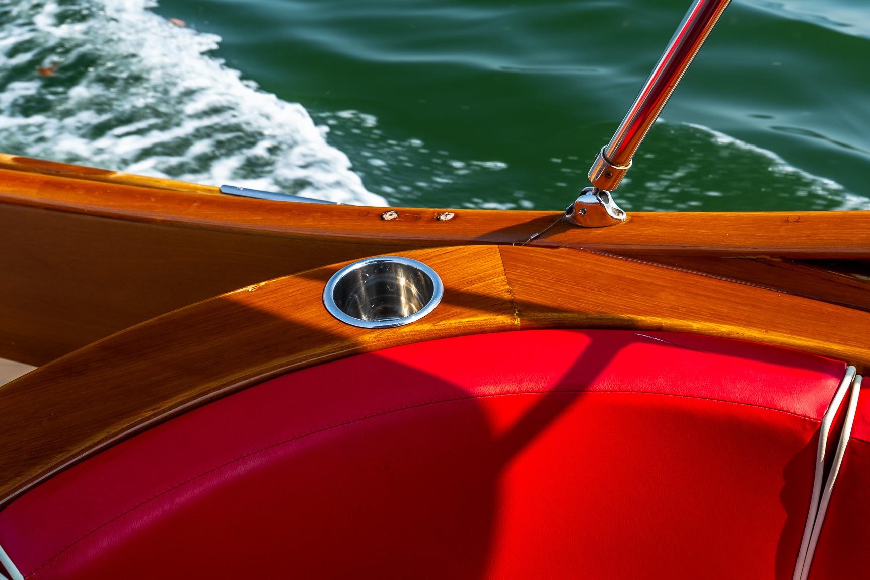 2005 Hinckley Talaria 29R boat with red seating and wooden details on water.