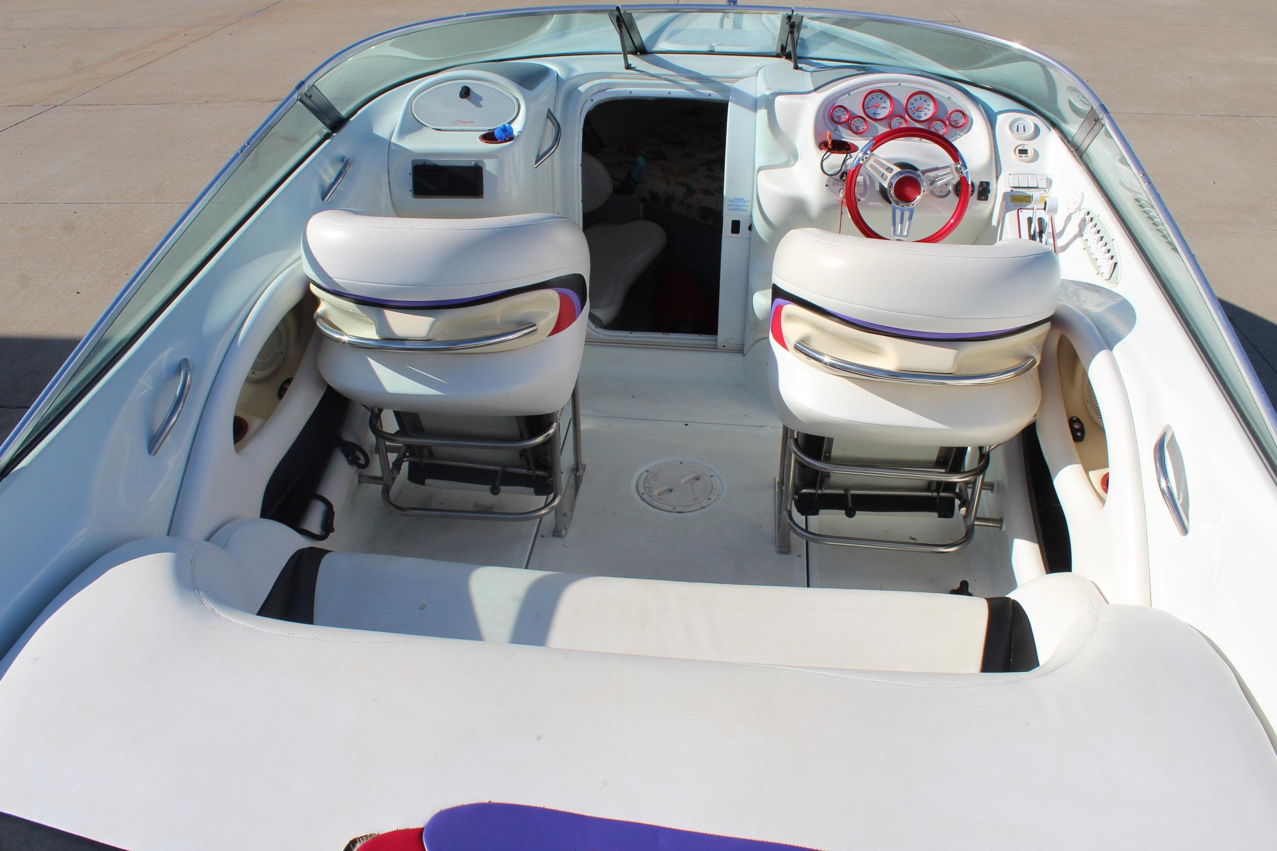 1996 Baja 232 boat interior with white seating and red steering wheel.