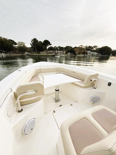 2016 Cobia 296 Center Console boat interior with seating and table on calm water.