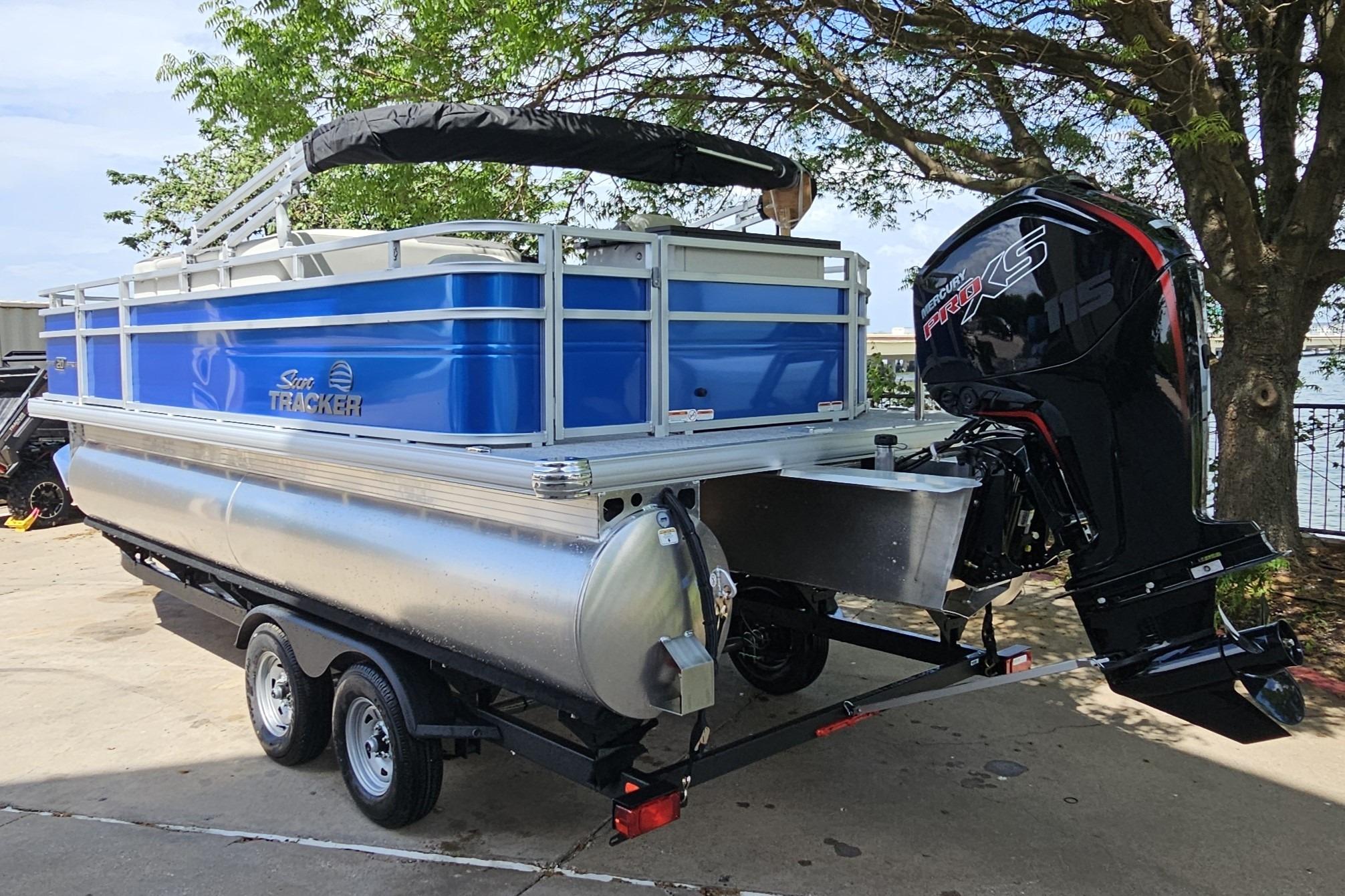 2026 Sun Tracker Fishin' Barge 20 DLX pontoon boat on trailer, parked outdoors.