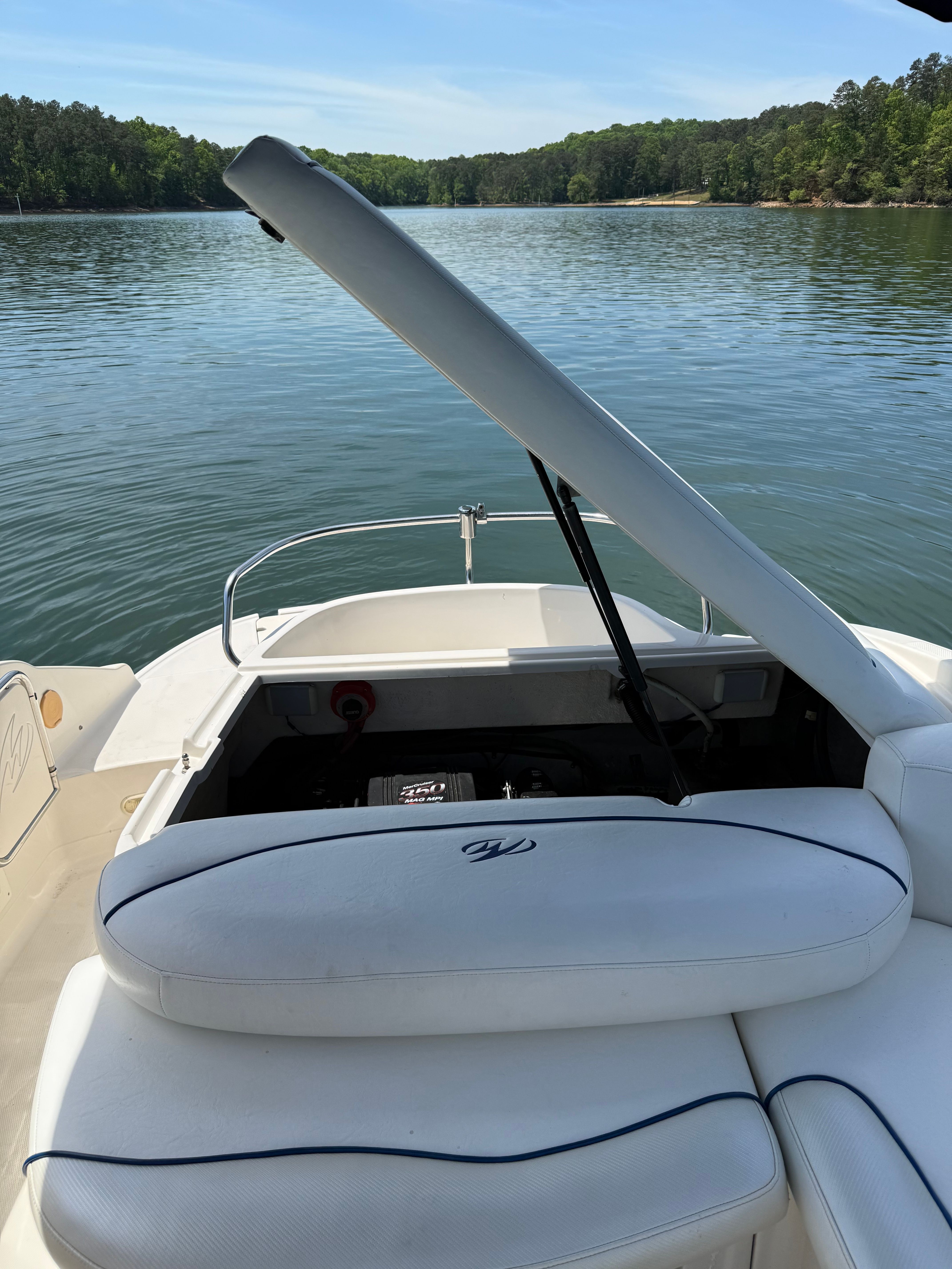 A 2005 Monterey 223 Explorer Sport on a calm lake with a wooded shoreline.