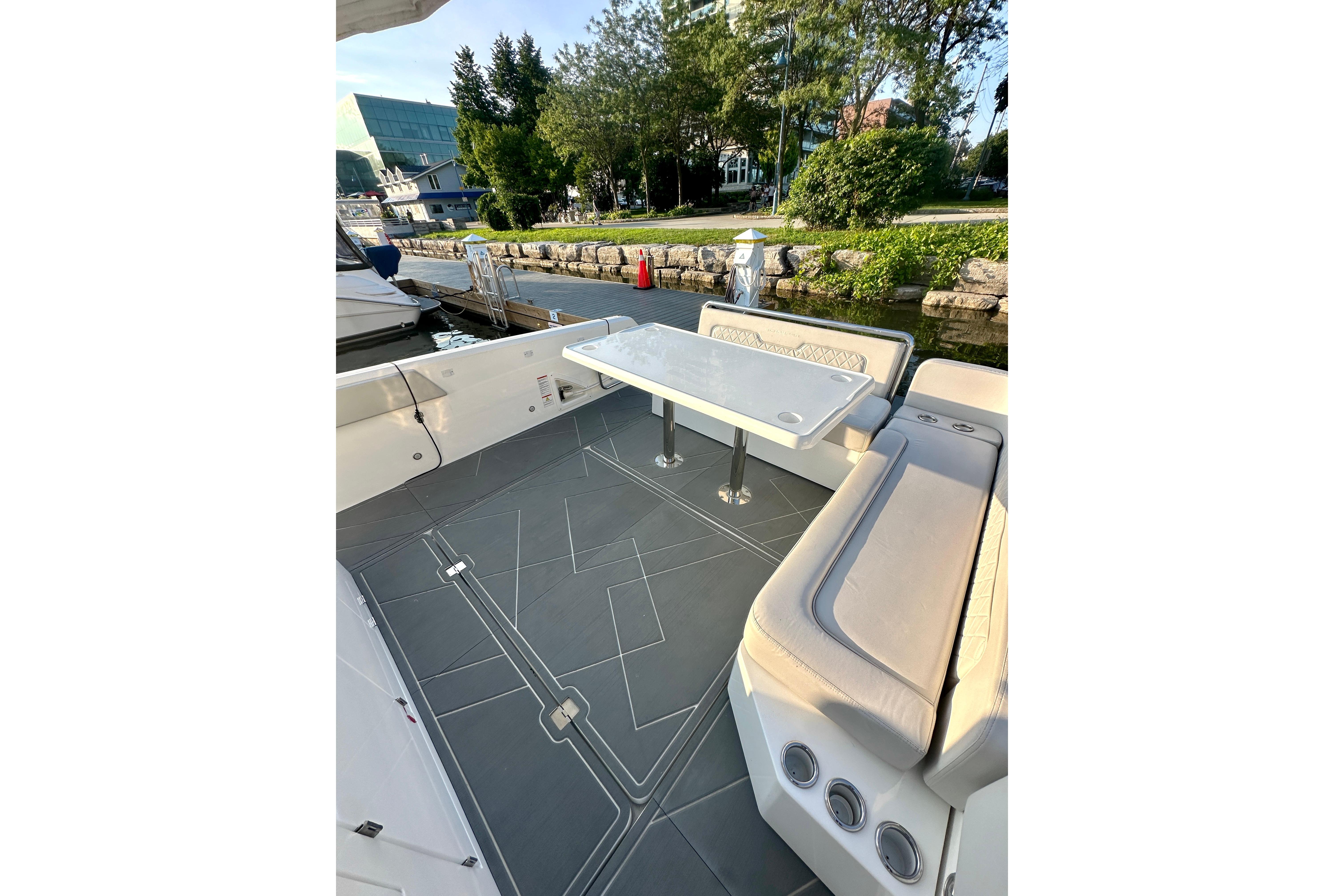2022 Schaefer V33 boat interior with seating and table, docked by a scenic waterfront.