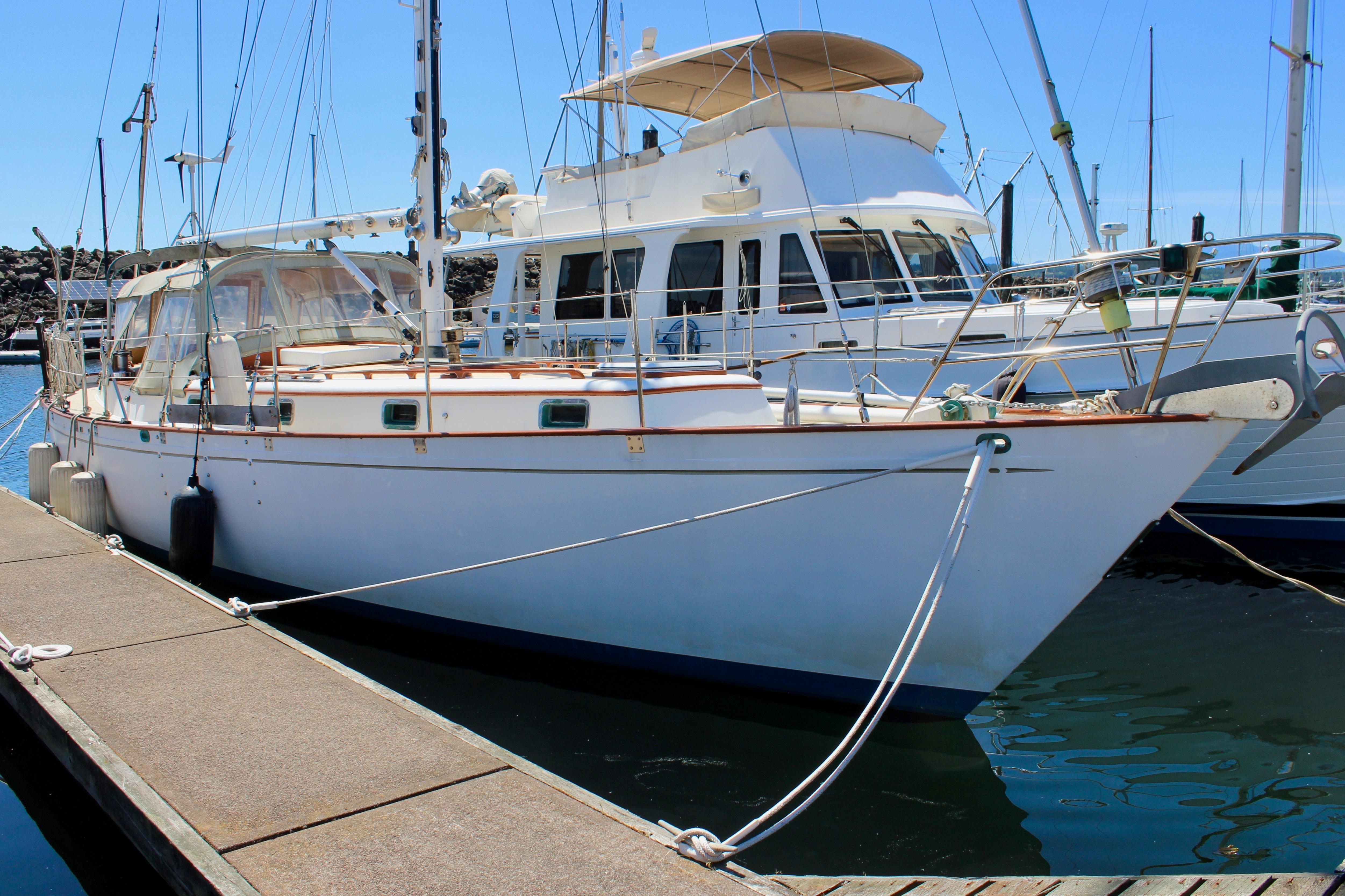 1981 Kelly Peterson 46 sailboat docked at marina, clear blue sky background.