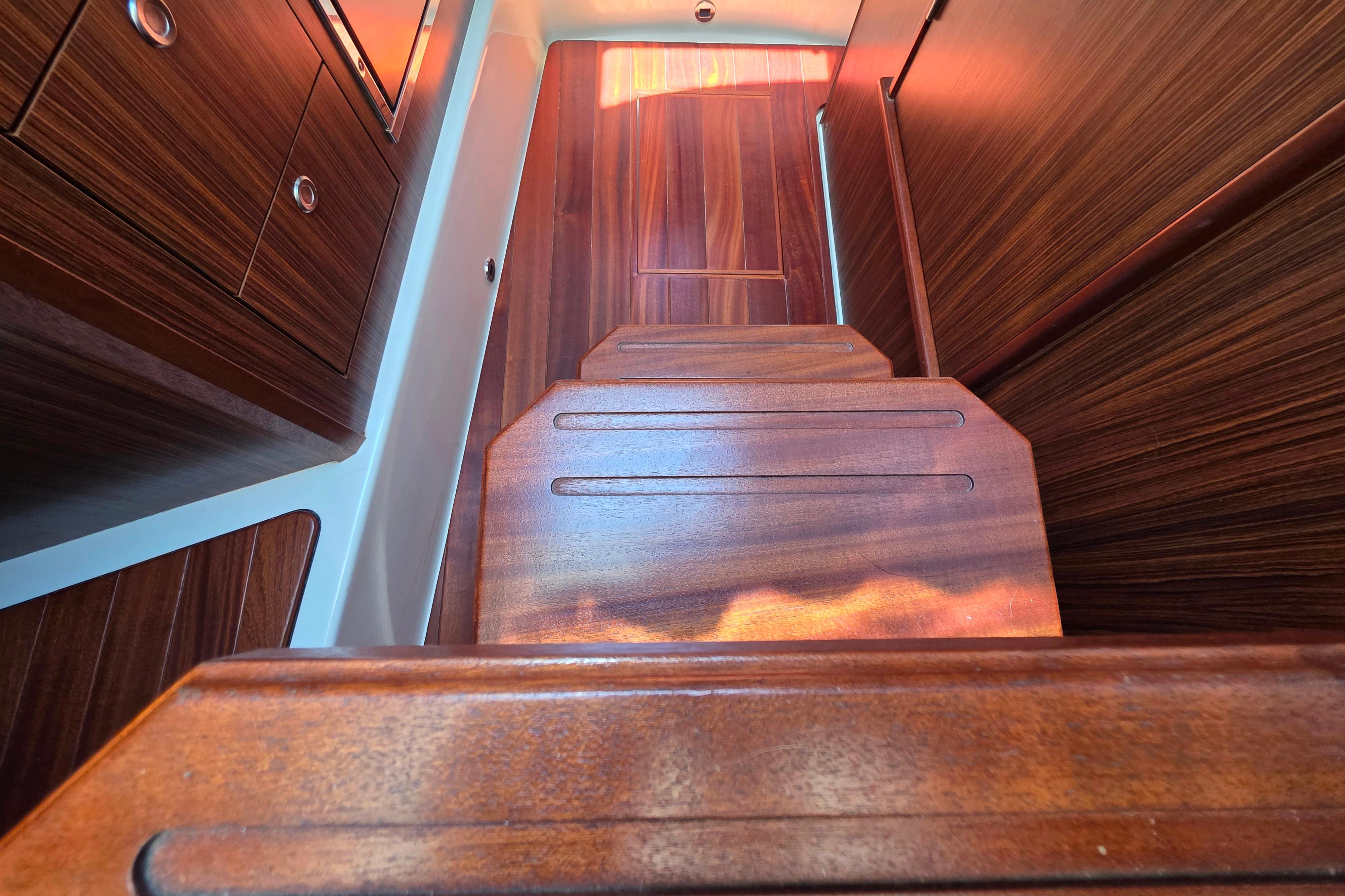 Interior view of 2020 Pursuit OS 325 Offshore boat with wooden stairs and cabinetry.