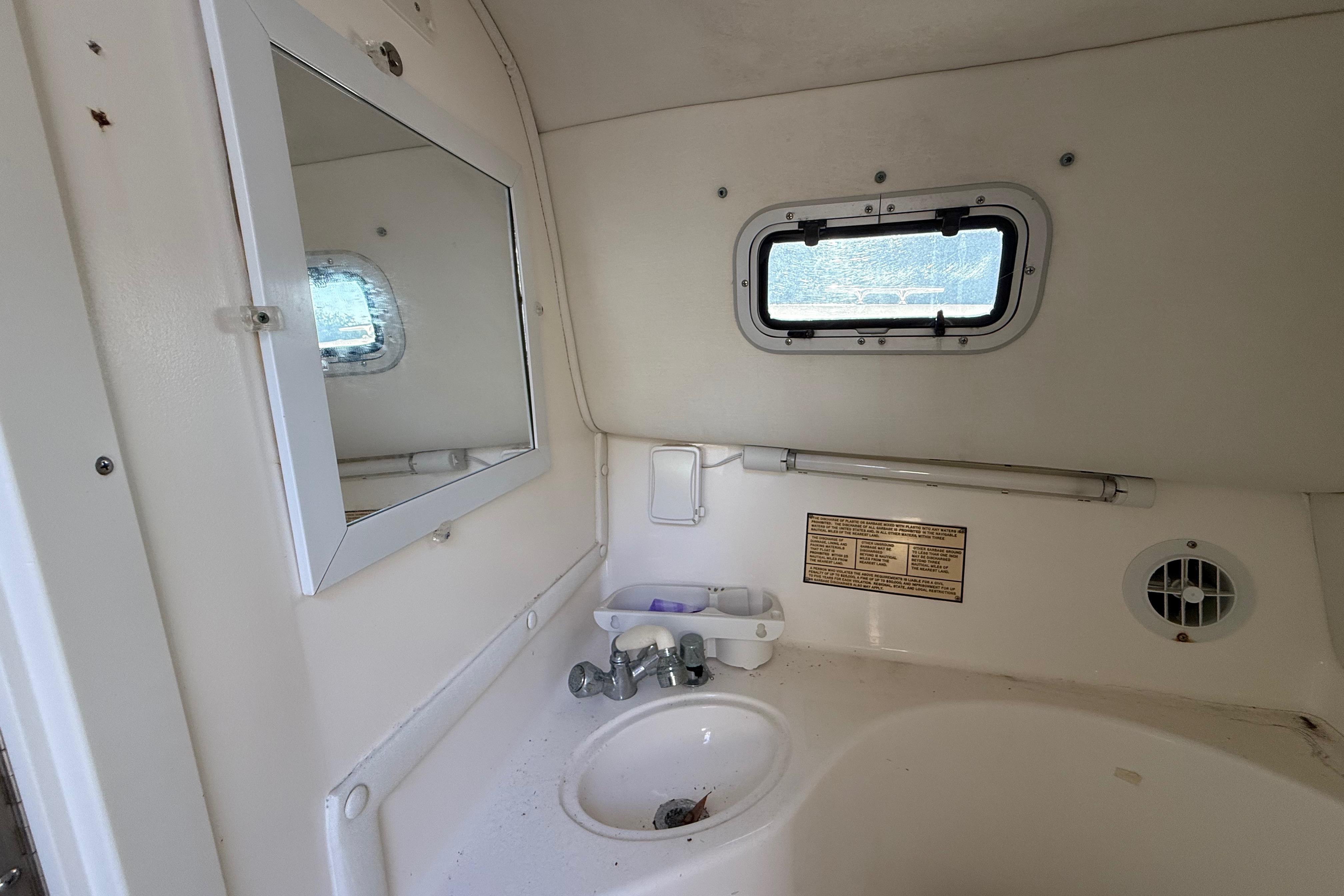 Interior of 2002 Century 2900 Walk-Around boat bathroom with sink and mirror.