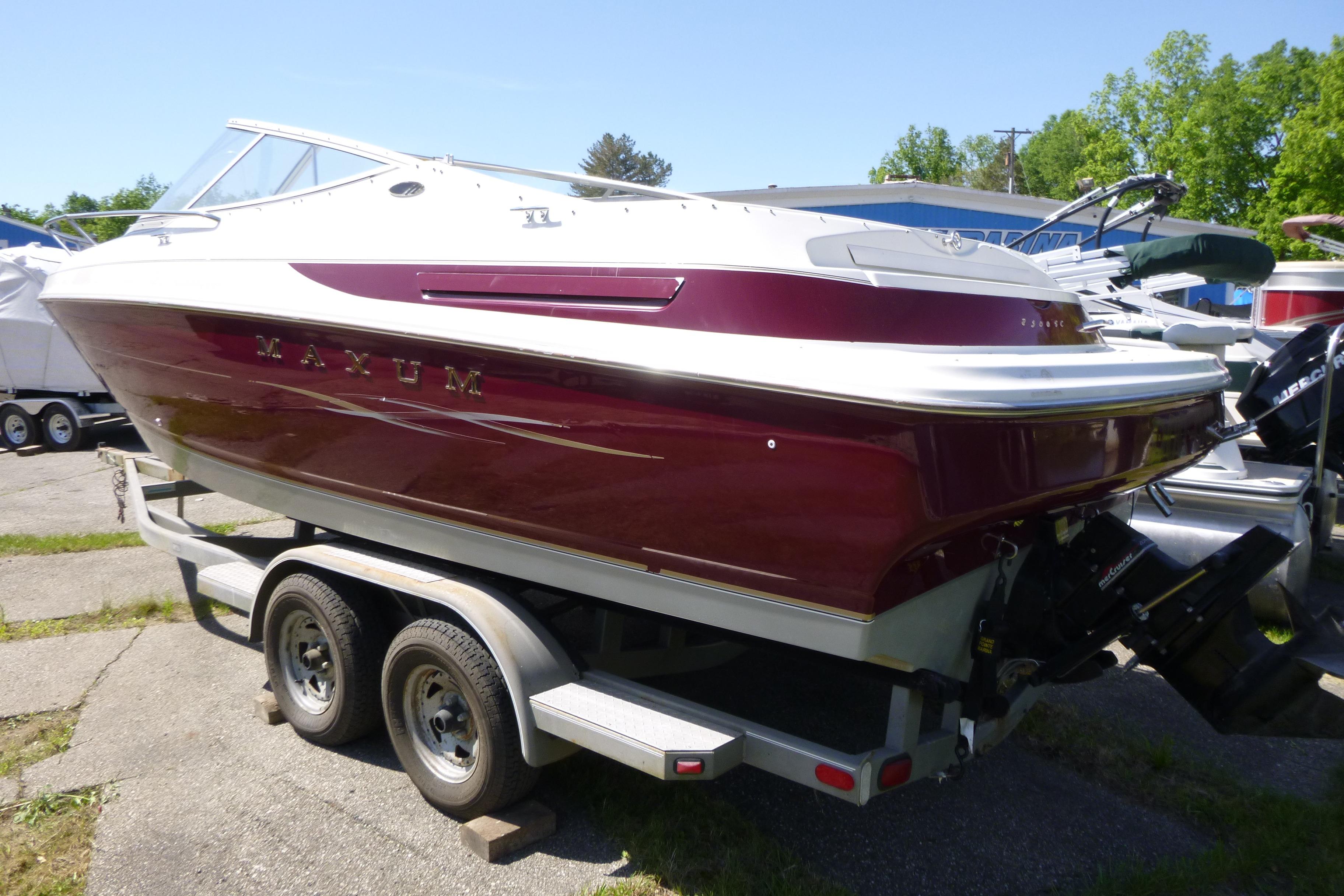 1998 Maxum 2300 SC boat on trailer, maroon and white, parked outdoors.
