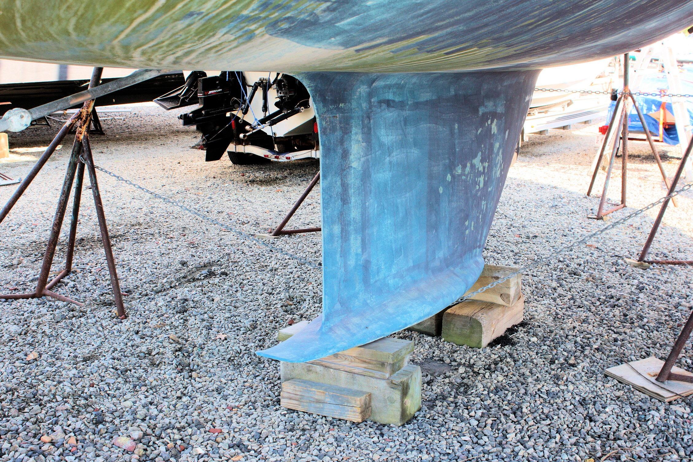 1987 Ericson 38-200 sailboat keel on stands in a gravel boatyard.