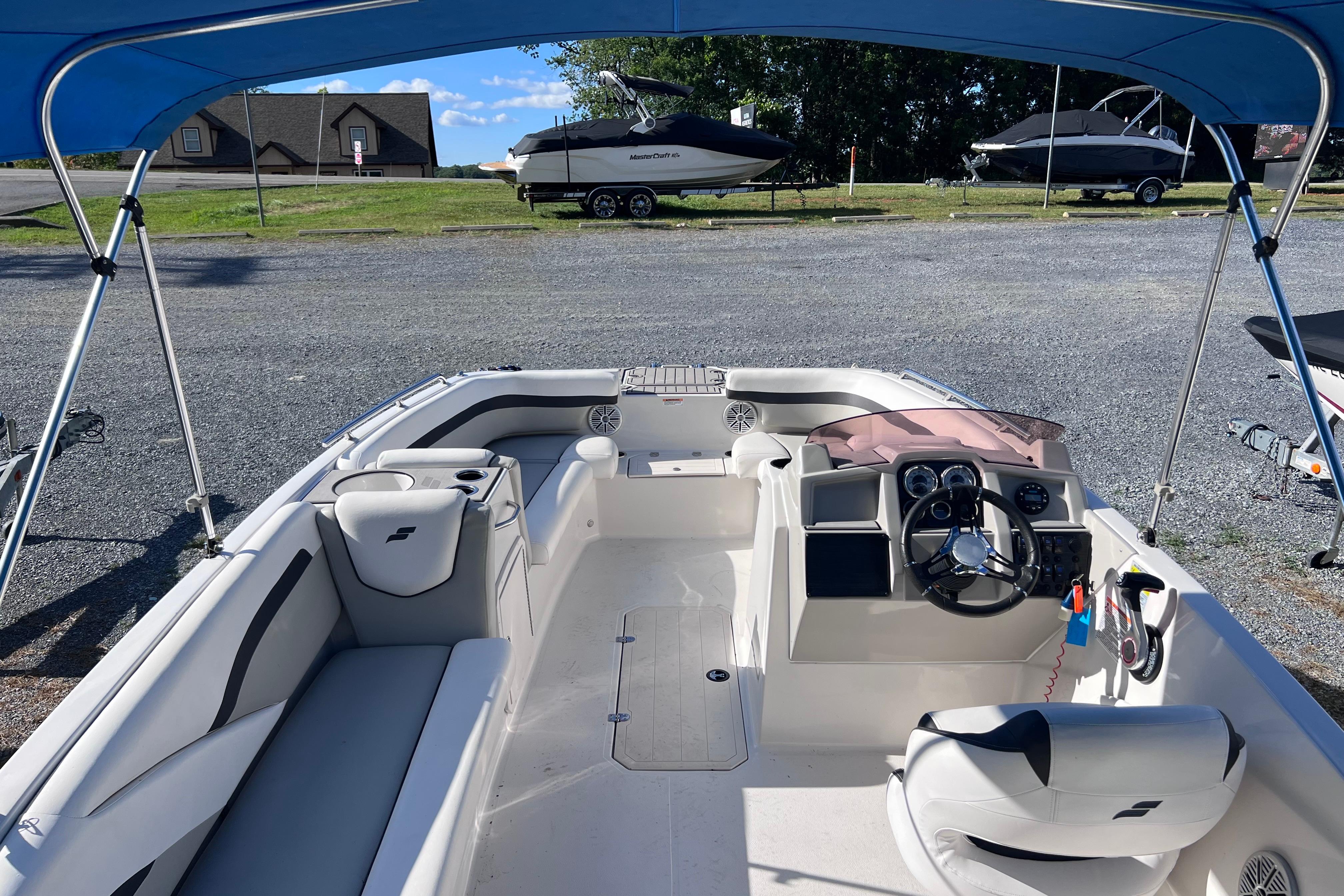 2021 Starcraft SVX 211 OB boat interior with steering wheel and seating under blue canopy.