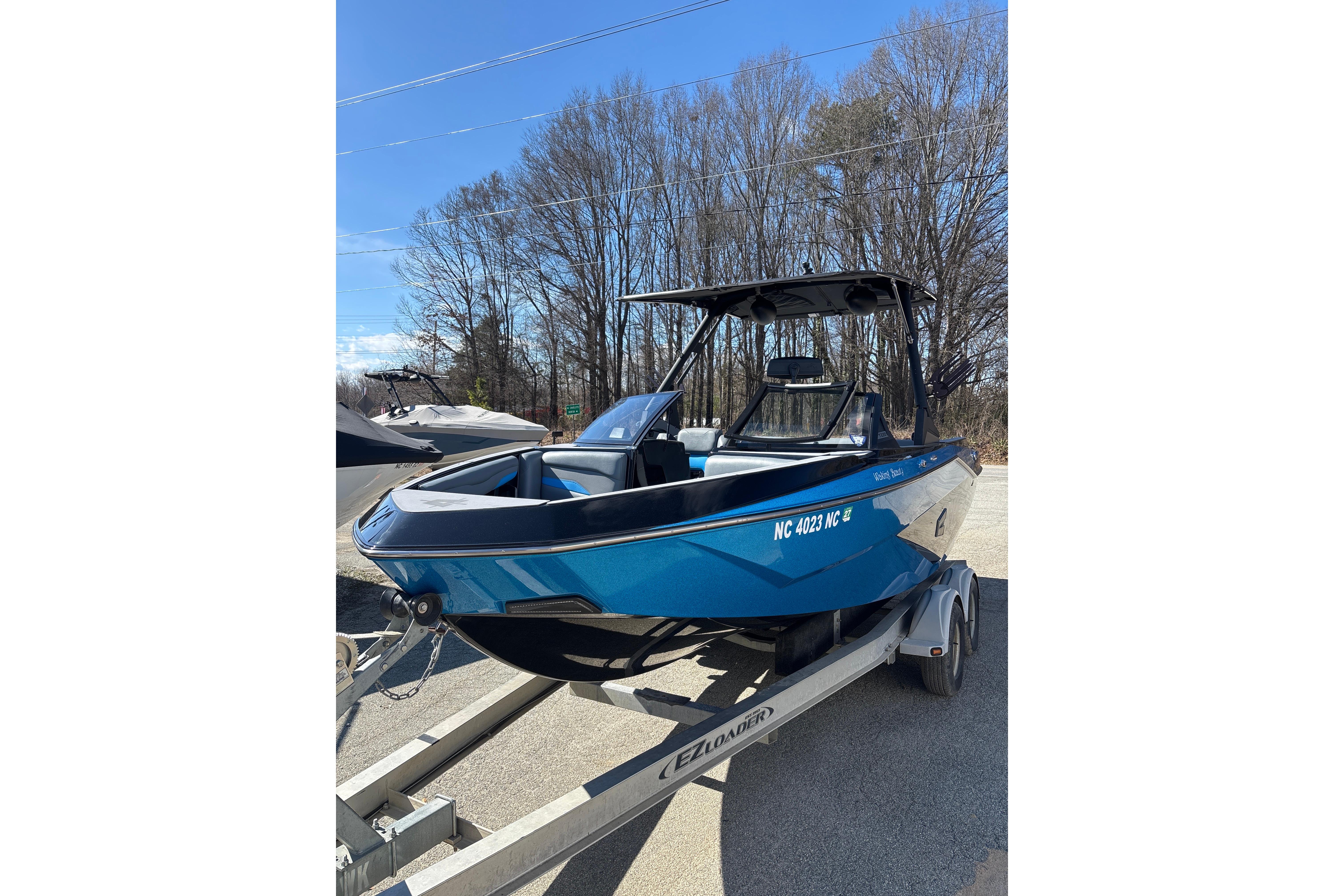 2023 Axis T220 boat on trailer, blue exterior, parked outdoors.