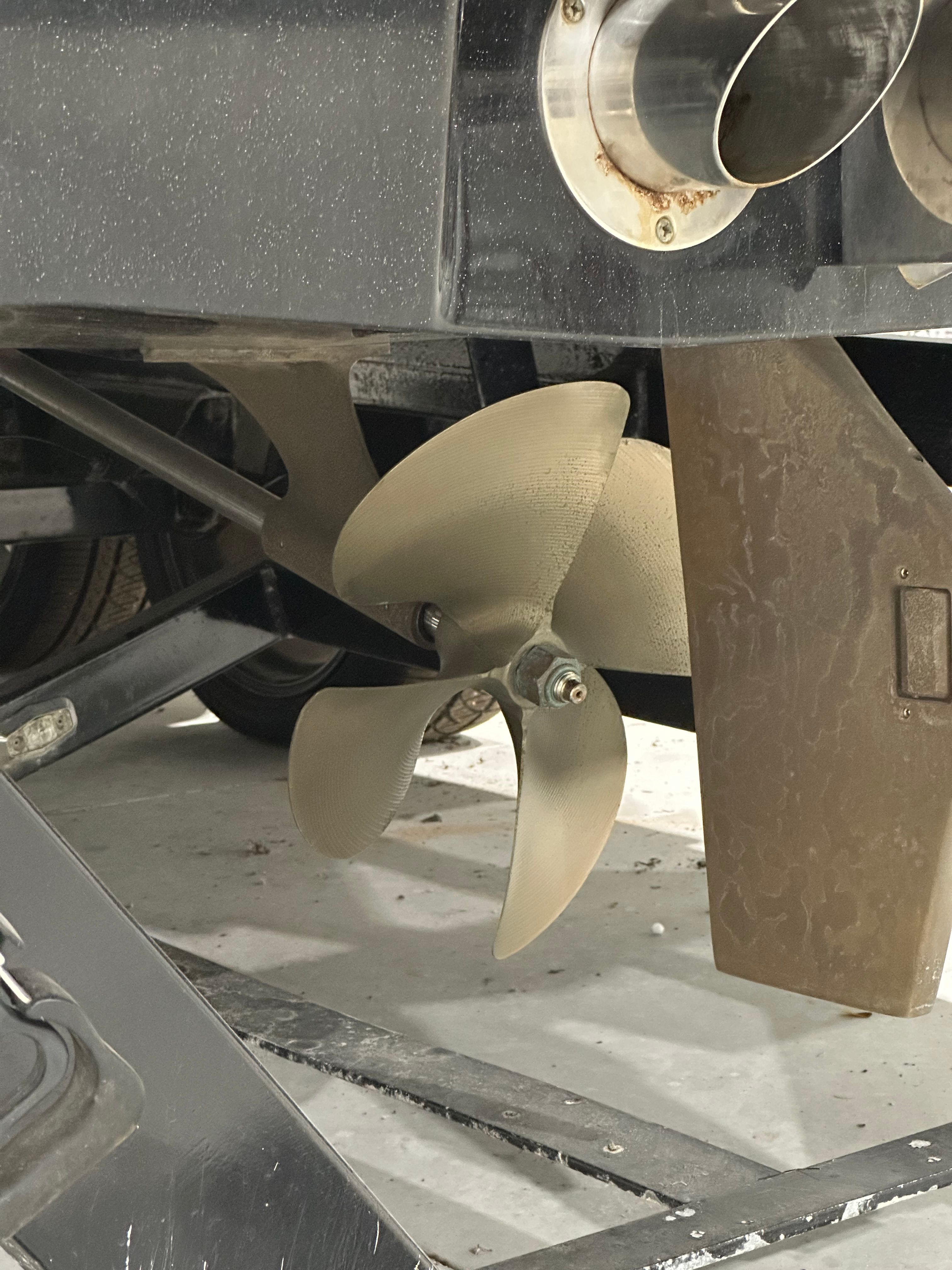 Close-up of a boat propeller and exhaust pipe on a trailer.
