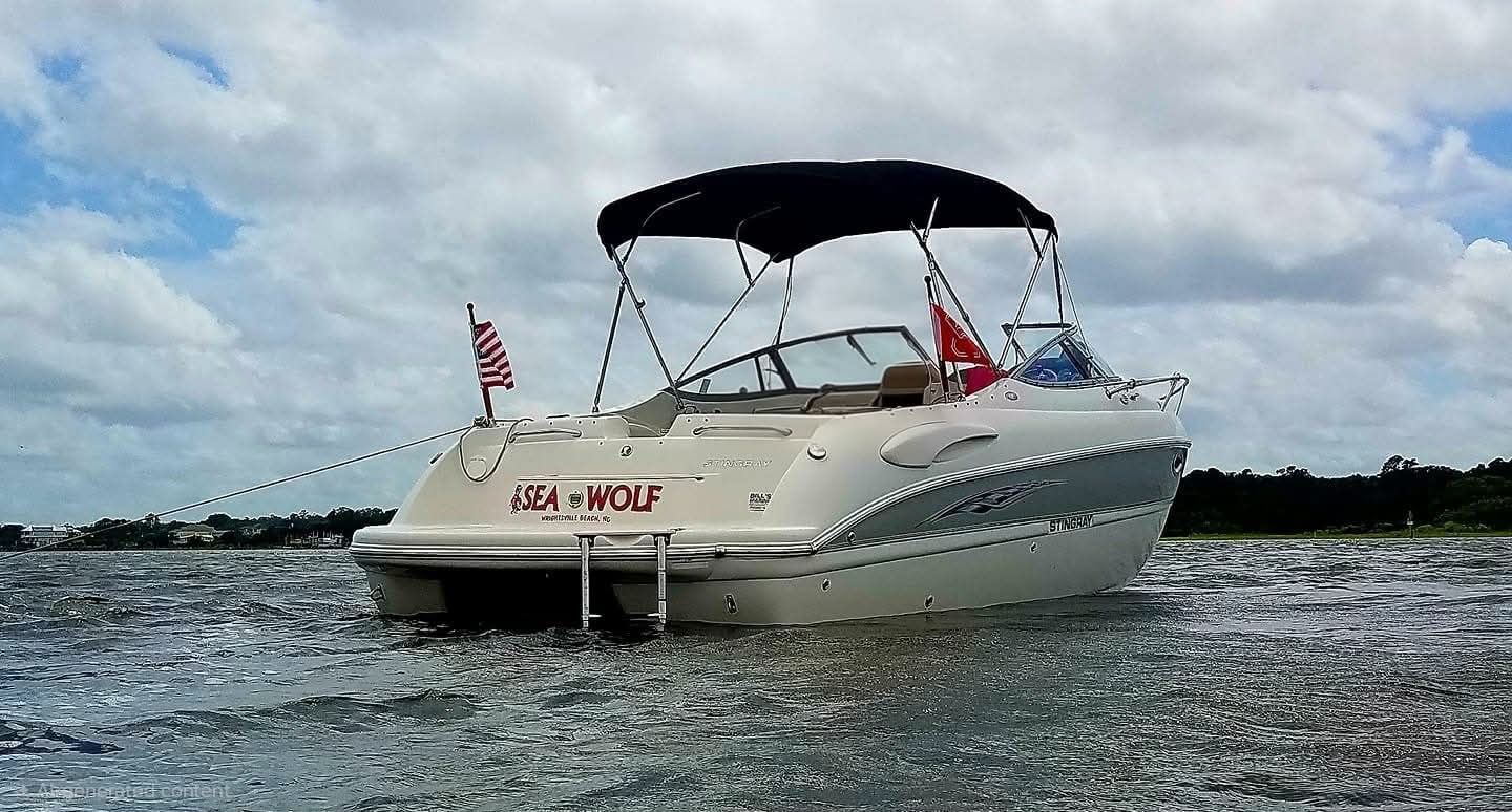 A 2006 Stingray 250 CR boat on the water with a black canopy.