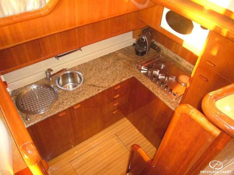 Luxurious kitchen interior of 2000 Ferretti Yachts 53 with wooden cabinetry and granite countertops.