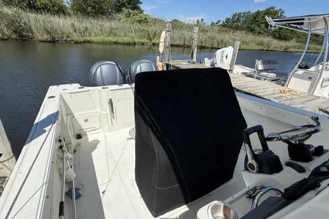2006 Sailfish 2660 CC boat docked by a serene riverbank.