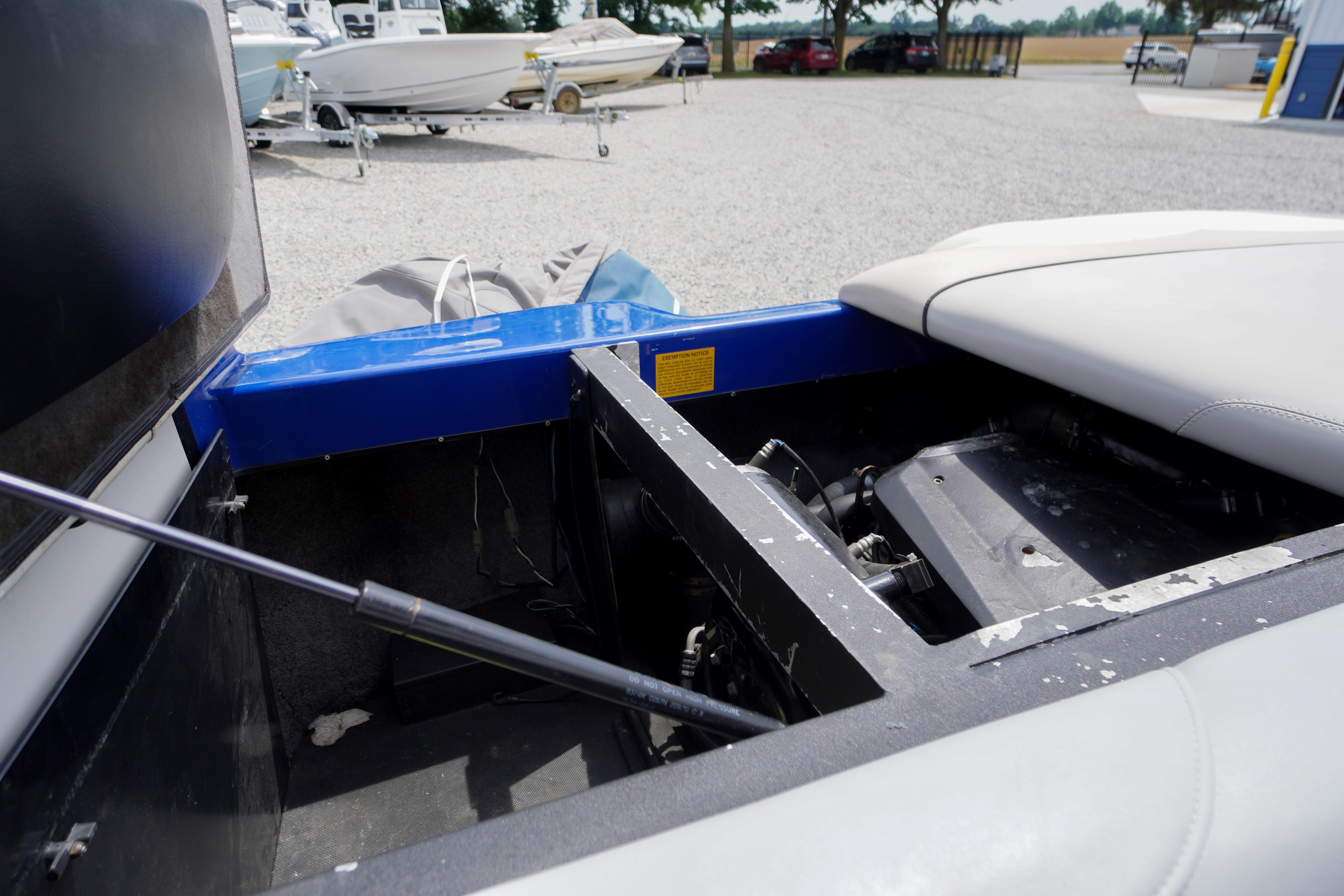 2011 Malibu Wakesetter 21 VLX engine compartment, open for maintenance, in a boatyard setting.
