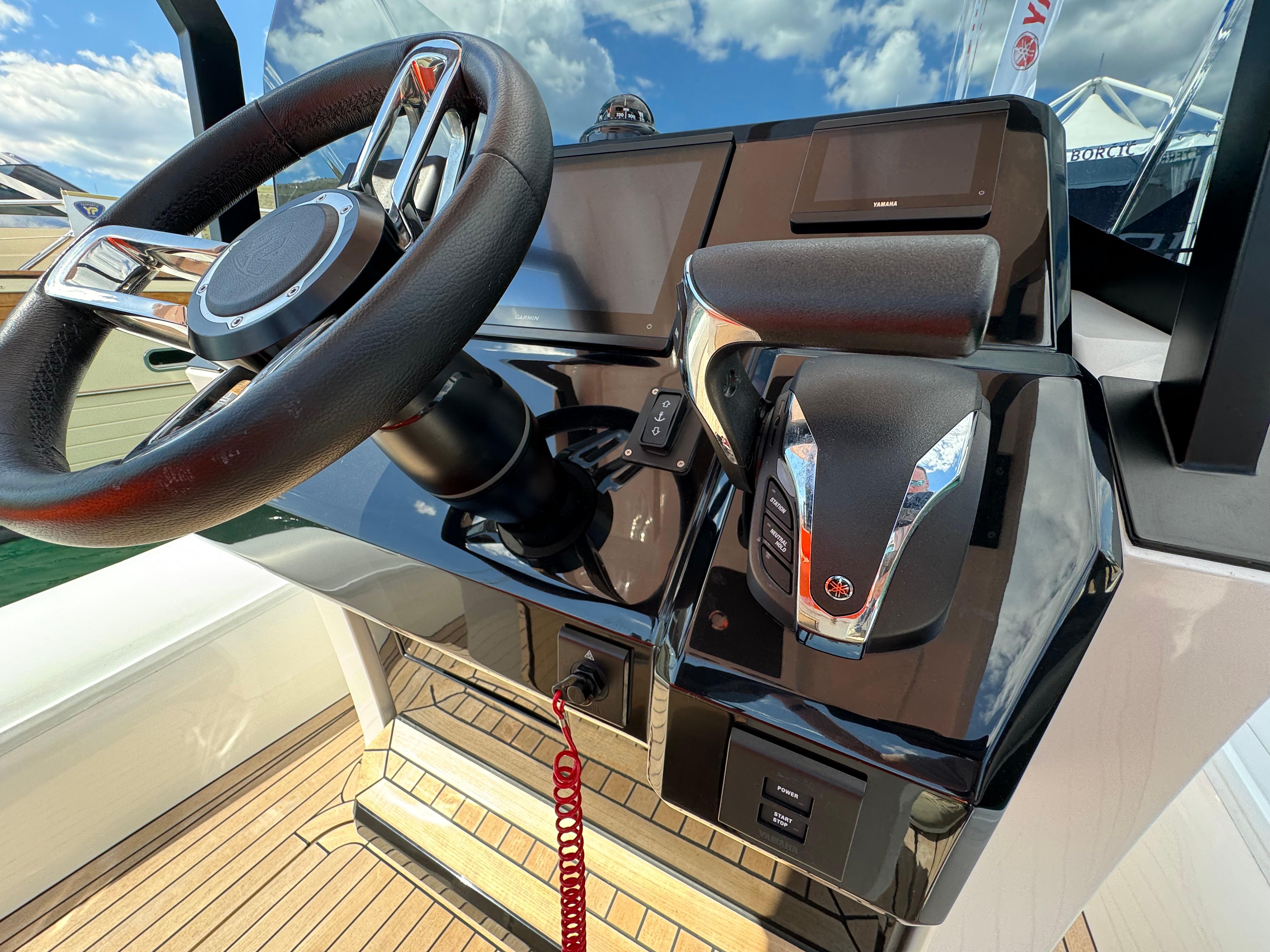 Control console of the 2025 SuperRib Open 27 boat with steering wheel and throttle.