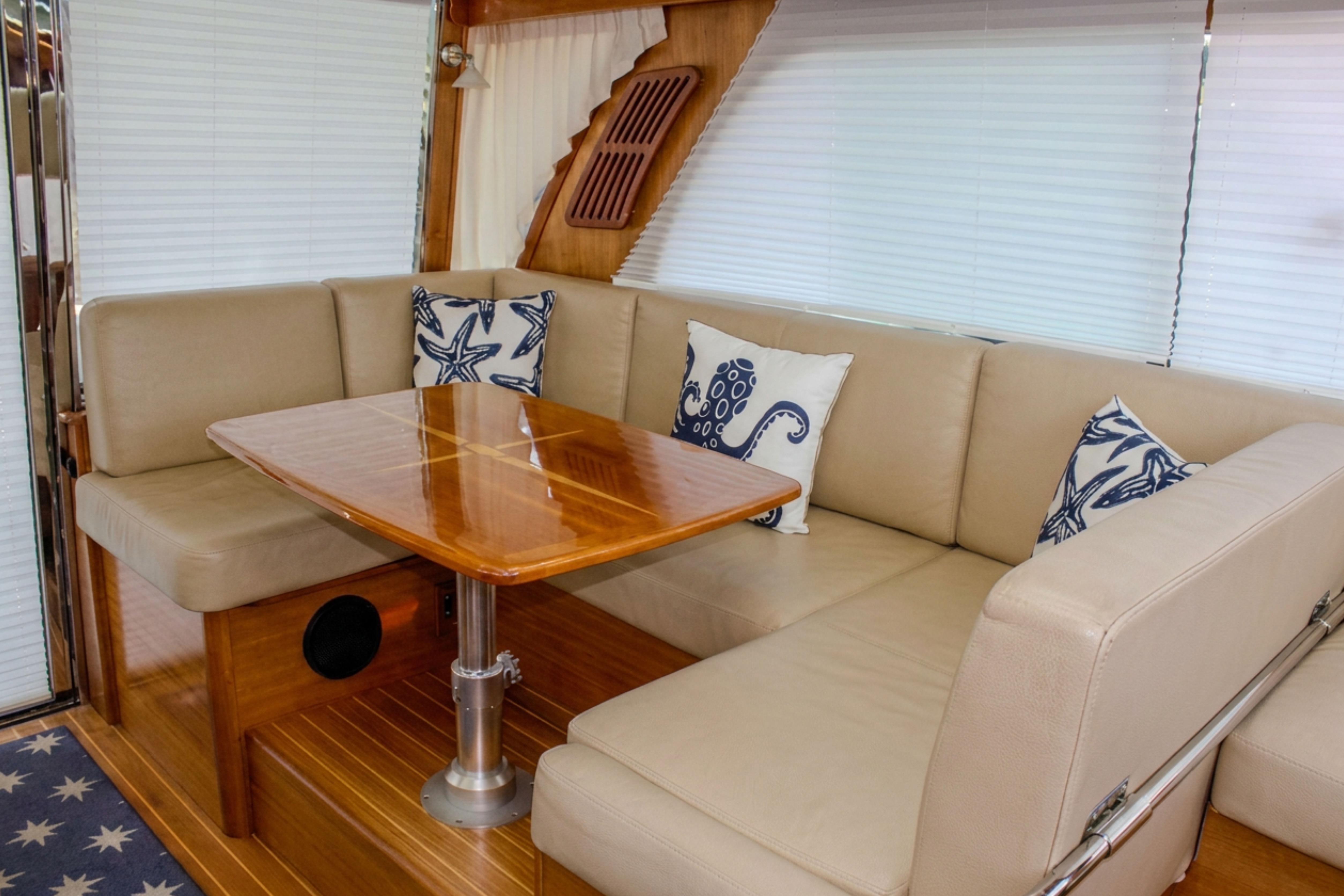 Luxurious interior of 2013 Sabre 38 Salon Express with beige seating and nautical-themed pillows.