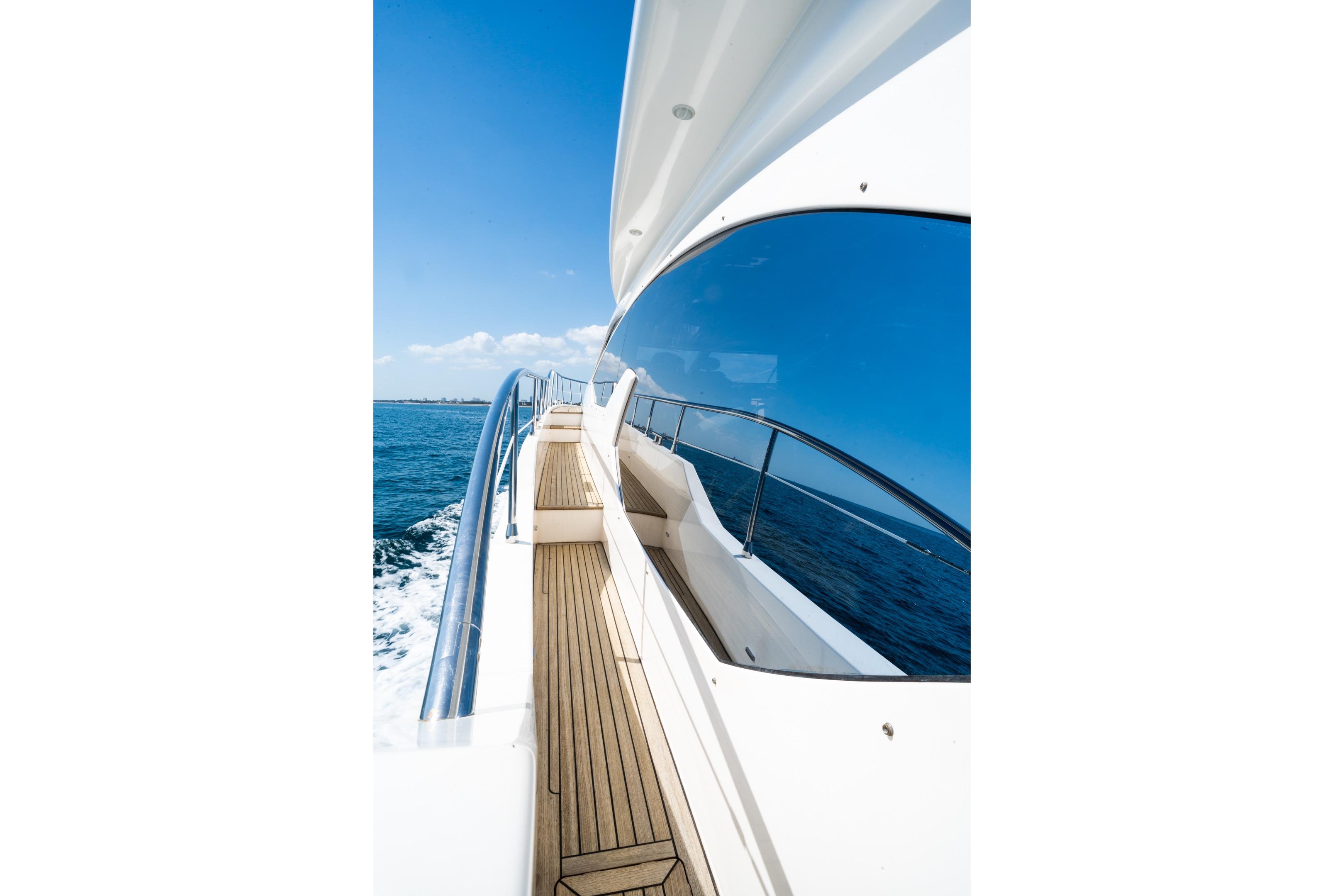 Side view of 2011 Azimut 70 yacht with wooden deck and ocean backdrop.