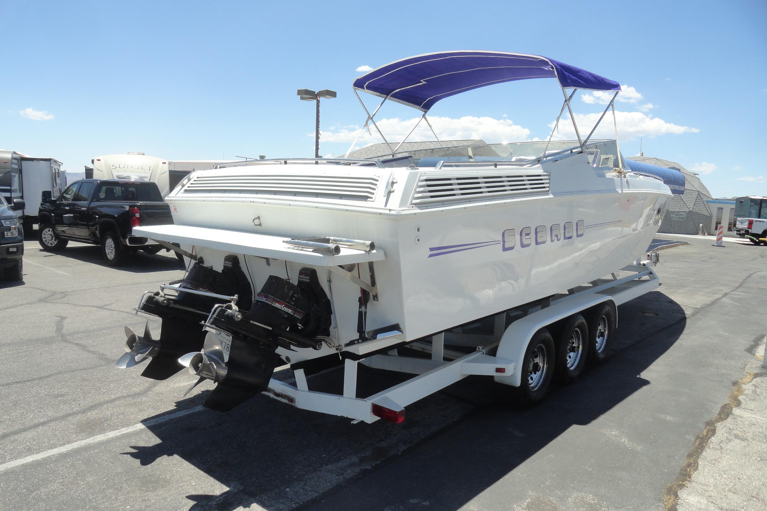 1988 Wellcraft 34 Scarab boat on trailer with blue canopy, parked outdoors.
