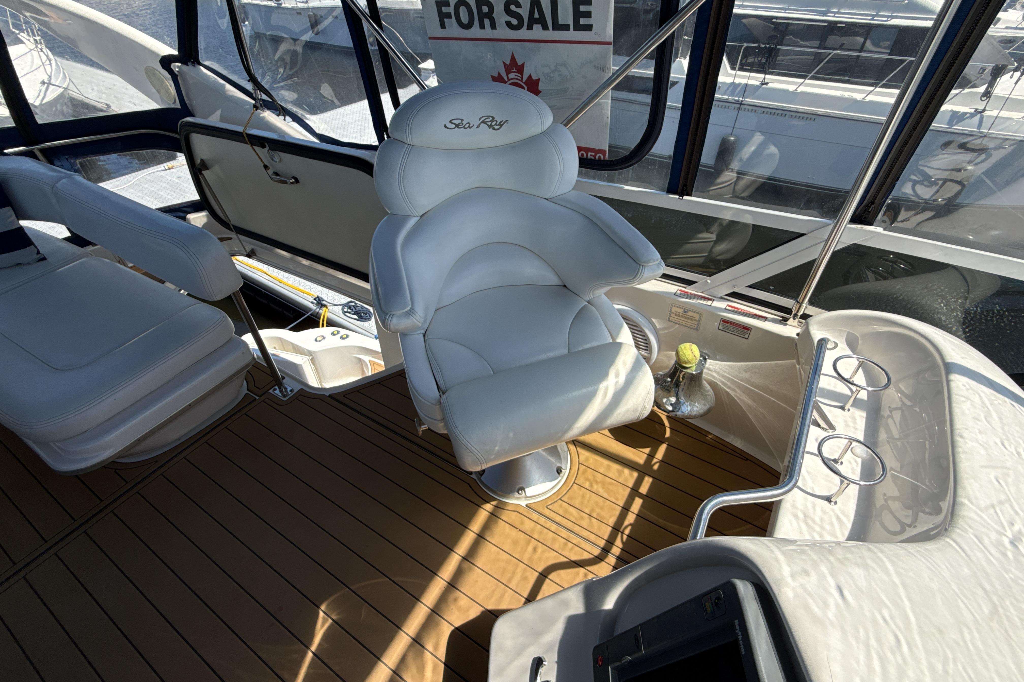 Luxurious 2001 Sea Ray 400 Sedan Bridge interior with white captain's chair and wooden flooring.