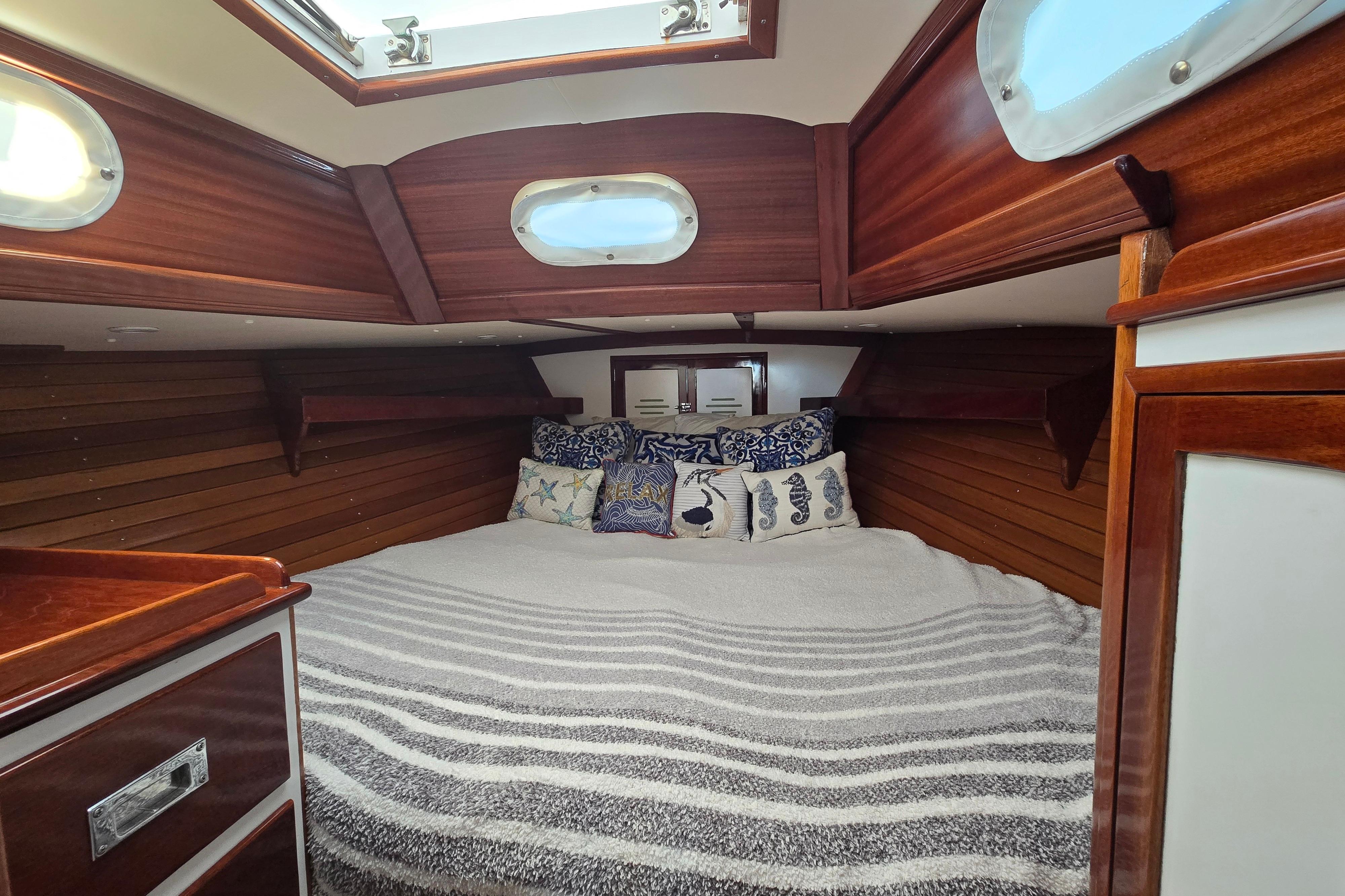 Cozy cabin interior of a 1970 Hinckley Bermuda 40 sailboat with striped bedding.
