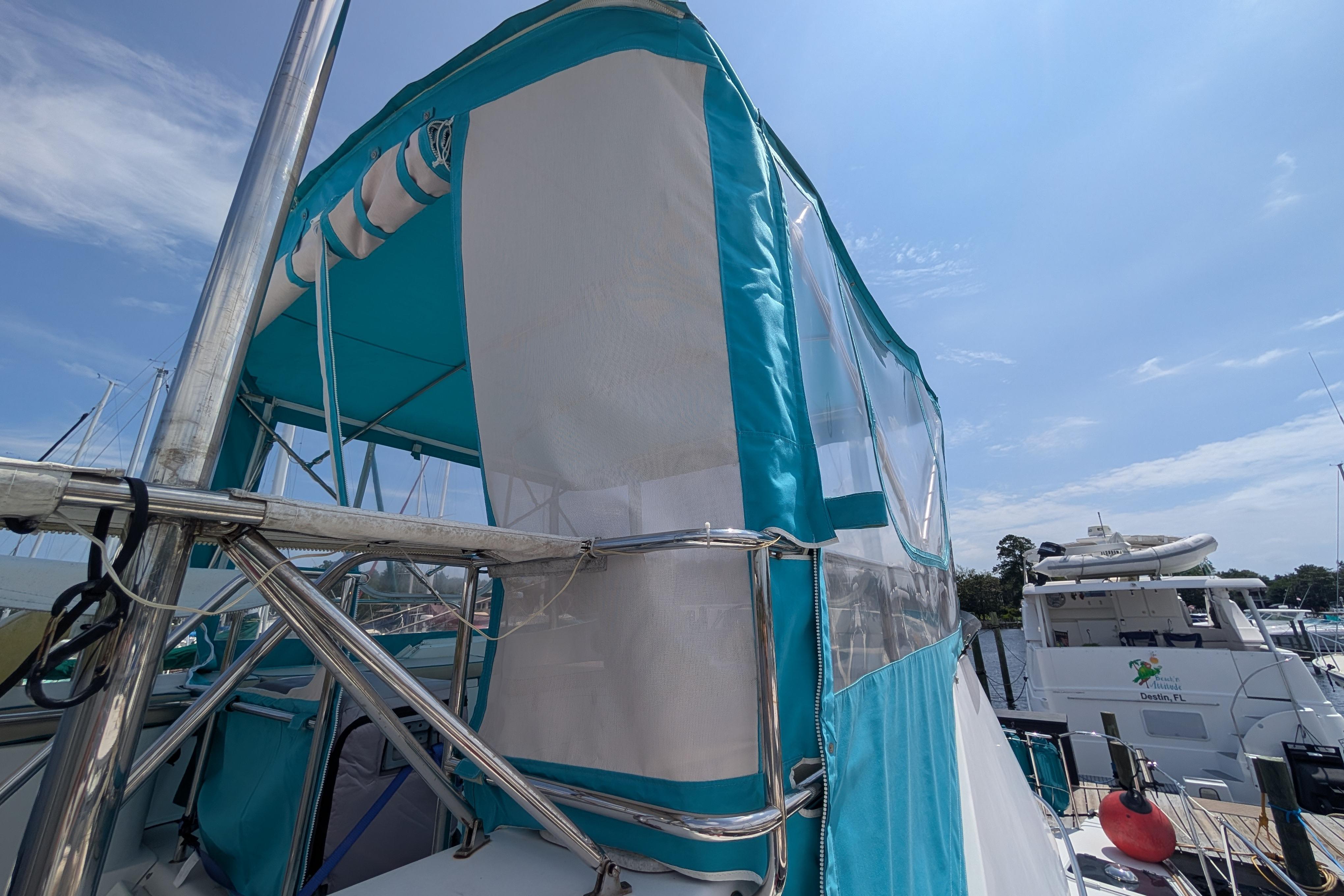 2004 PDQ 34 Powercat with turquoise canopy docked at marina under clear sky.