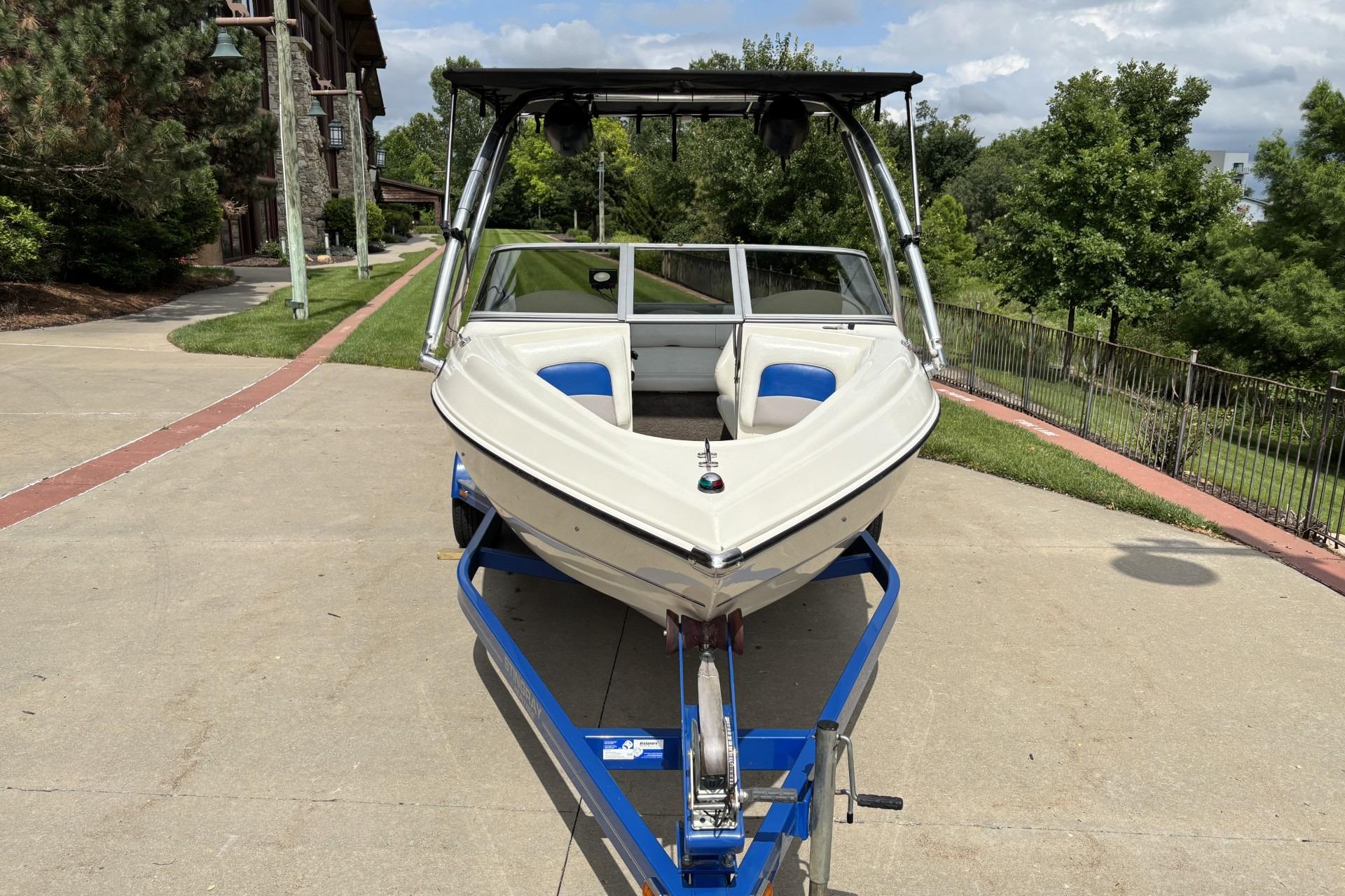 2007 Stingray 180 RX boat on trailer, parked outdoors with lush greenery background.