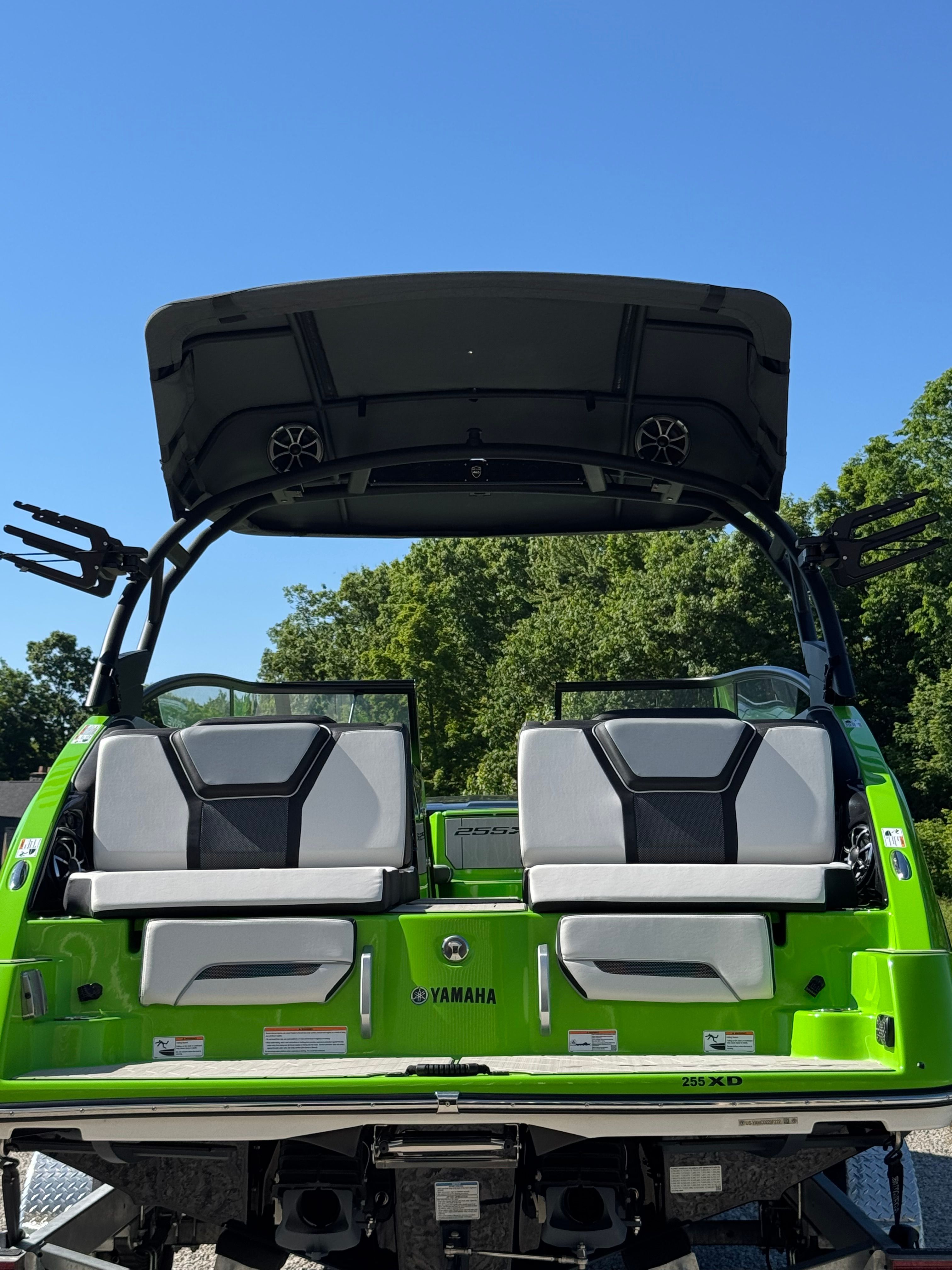 Yamaha 255XD 2022 with bright green stern and two cushioned seats, surrounded by trees.