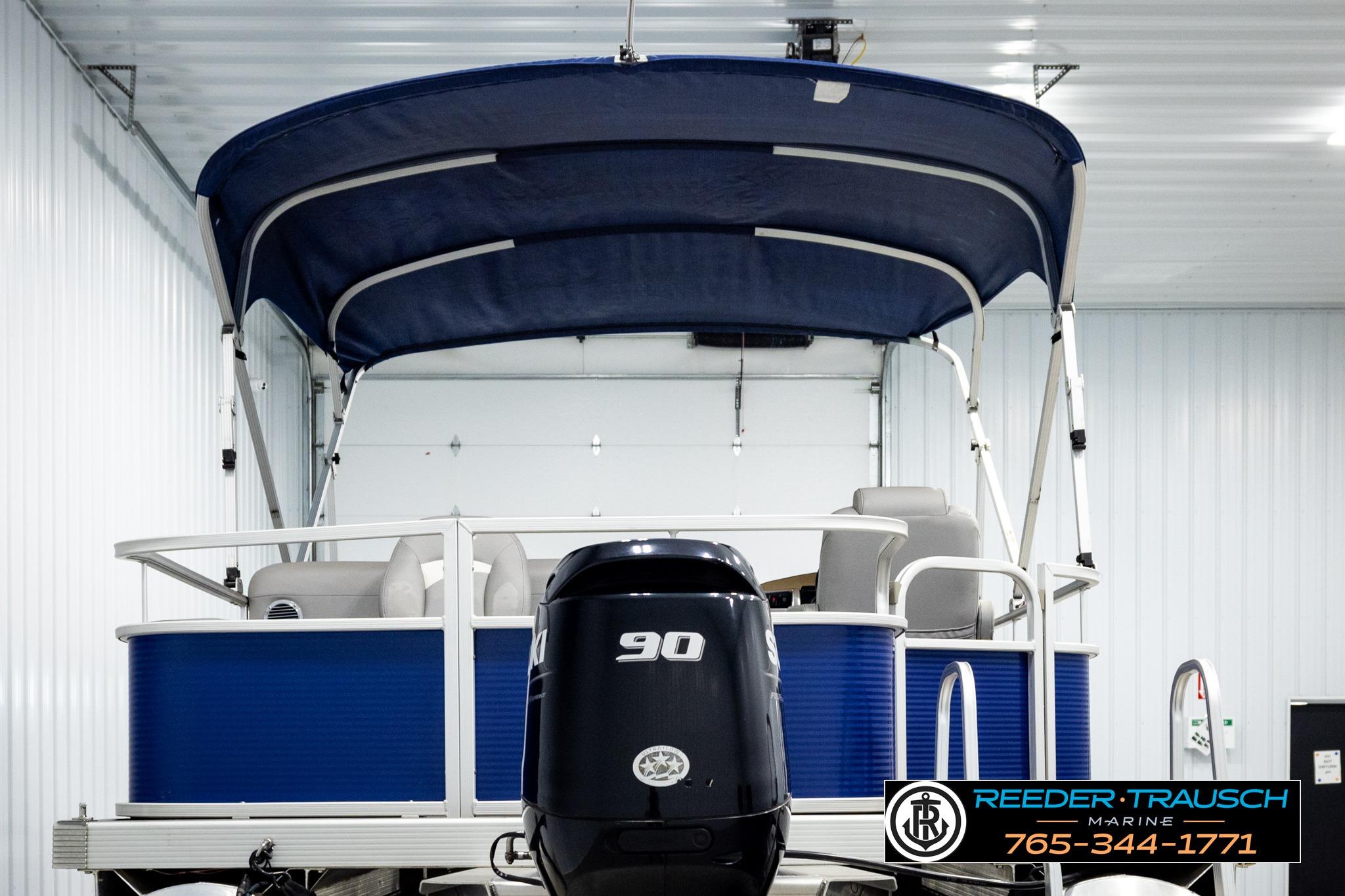 2021 Bennington 20 SV pontoon boat with blue canopy and 90 HP motor in showroom.