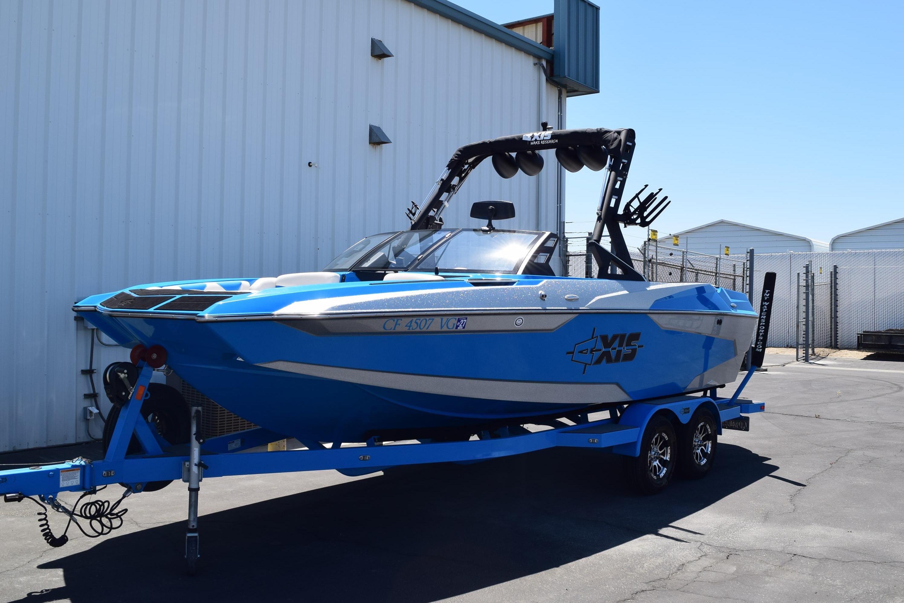 2019 Axis A22 boat in vibrant blue on a trailer, parked outdoors.